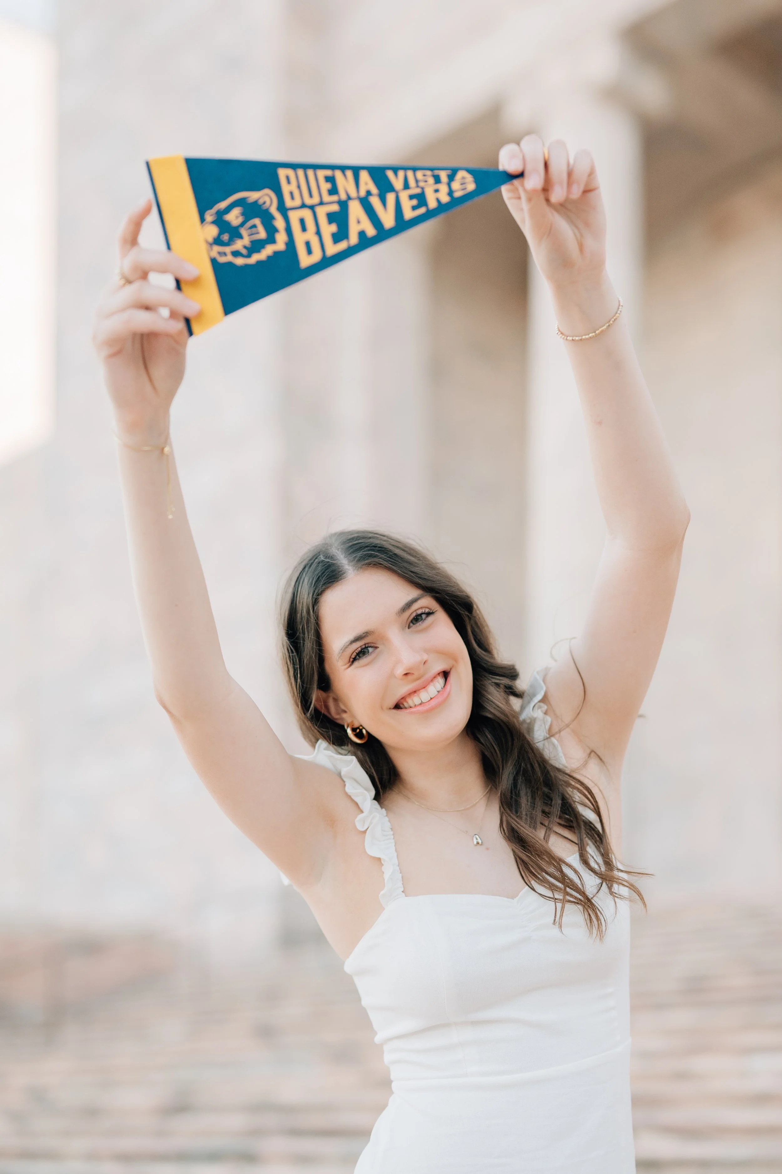 Girl raises college banner toward camera to celebrate where she is going to college.