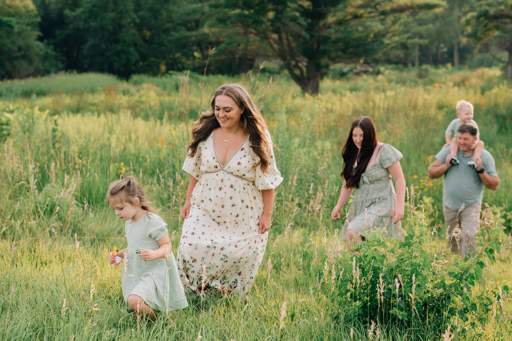 Family walks up a grassy hill during family photo session in Iowa.