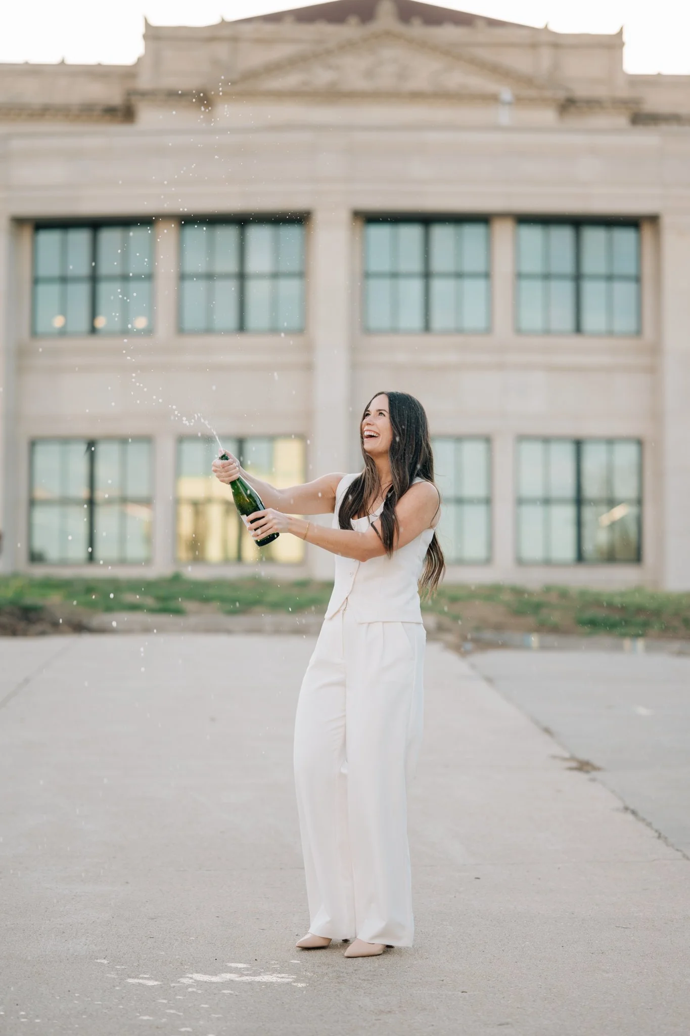 Student pops champagne to celebrate college graduation during graduation photography session in Omaha.
