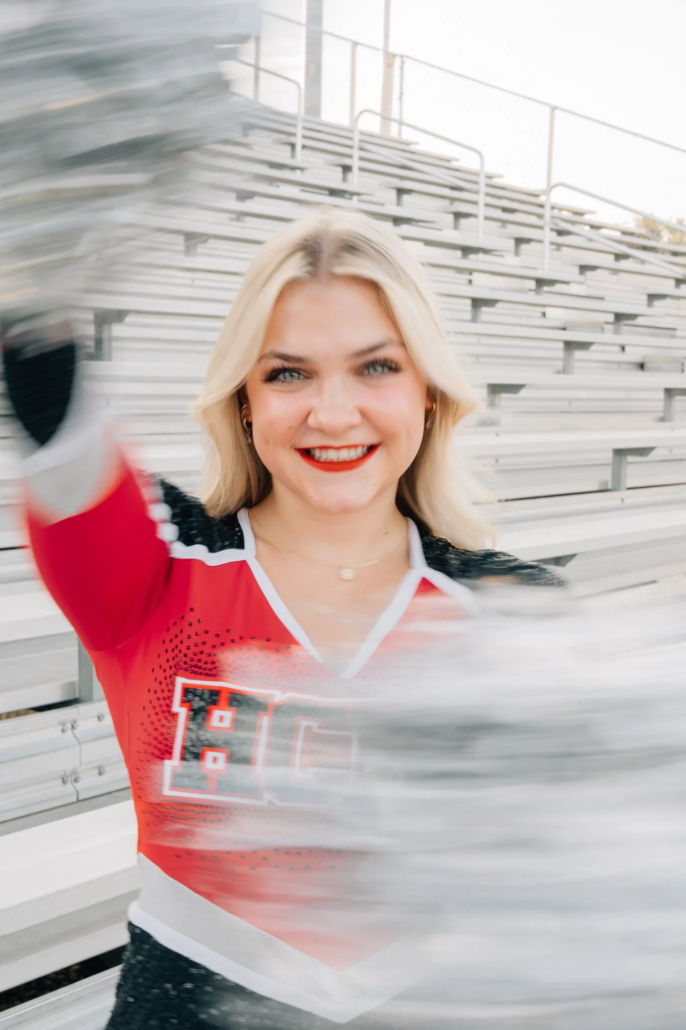 Motion blur image of a senior rotating her cheer poms around her to create a creative, motion filled senior picture.