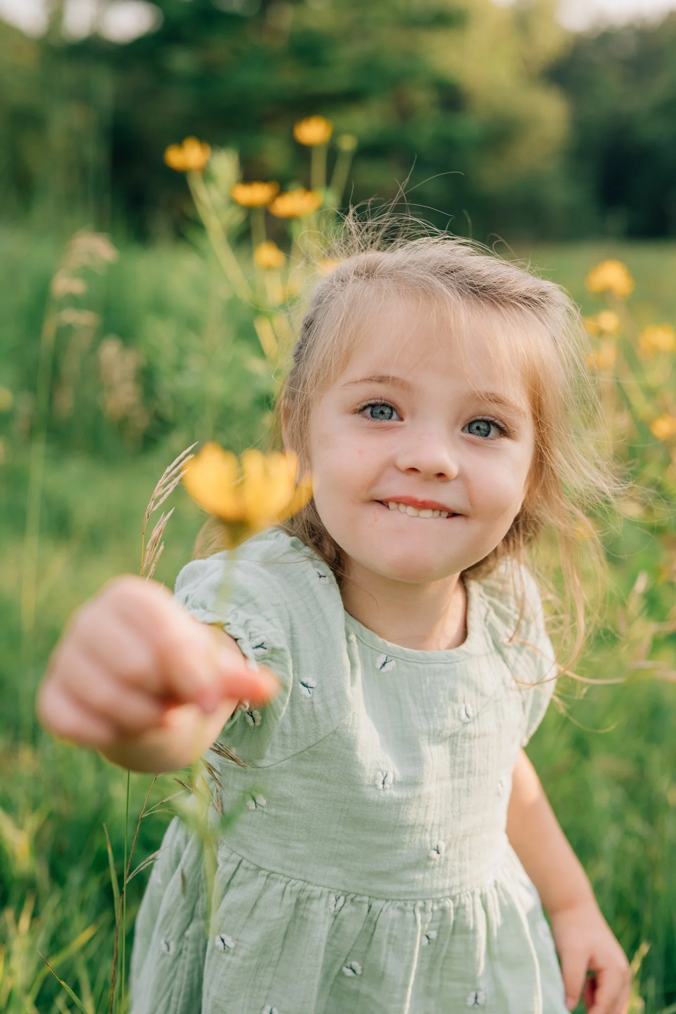 little girl handing flower to the camera during family photo session.
