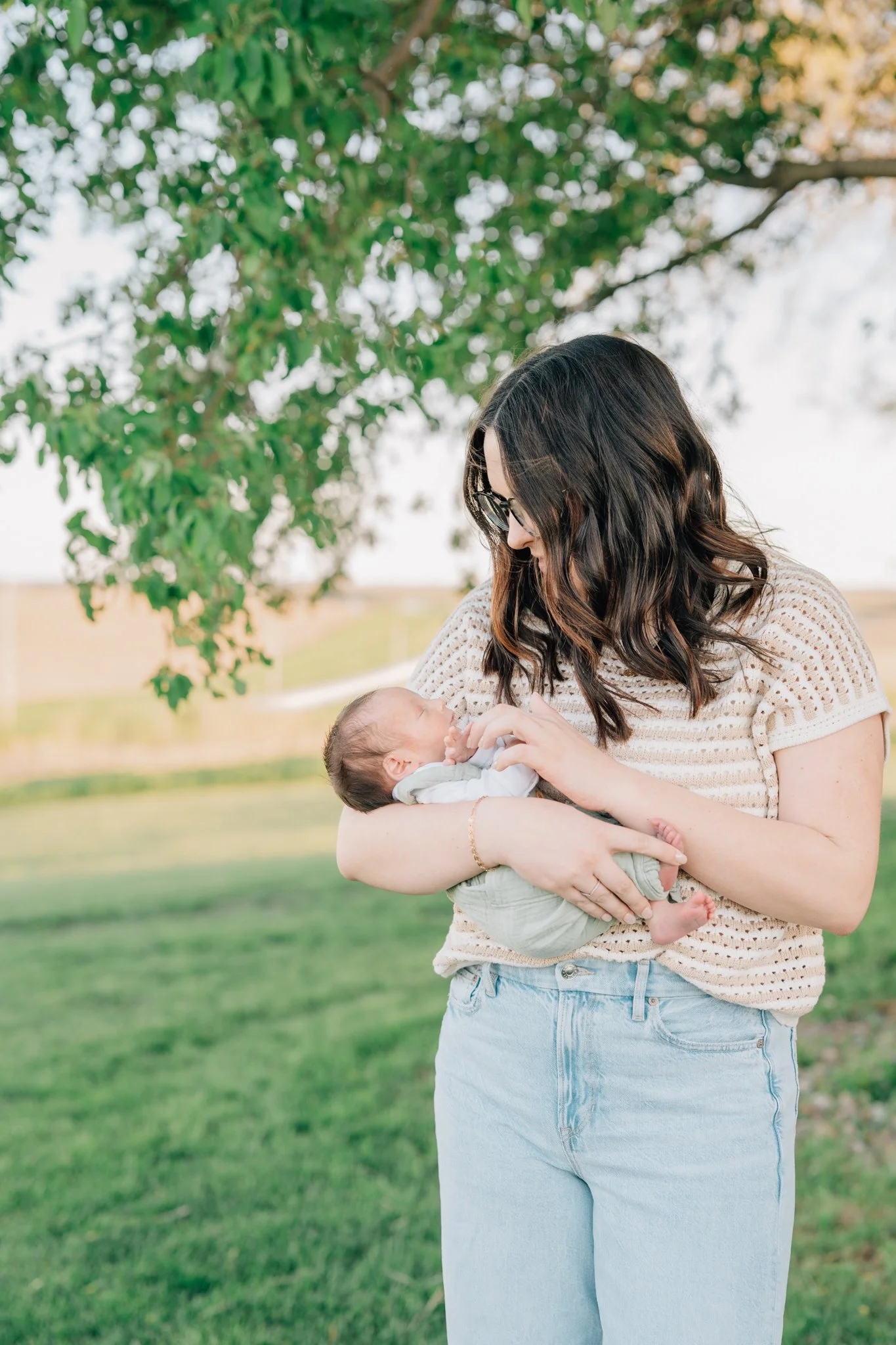 Lifestyle newborn photo of mom holding her newborn son in her front yard in Iowa.