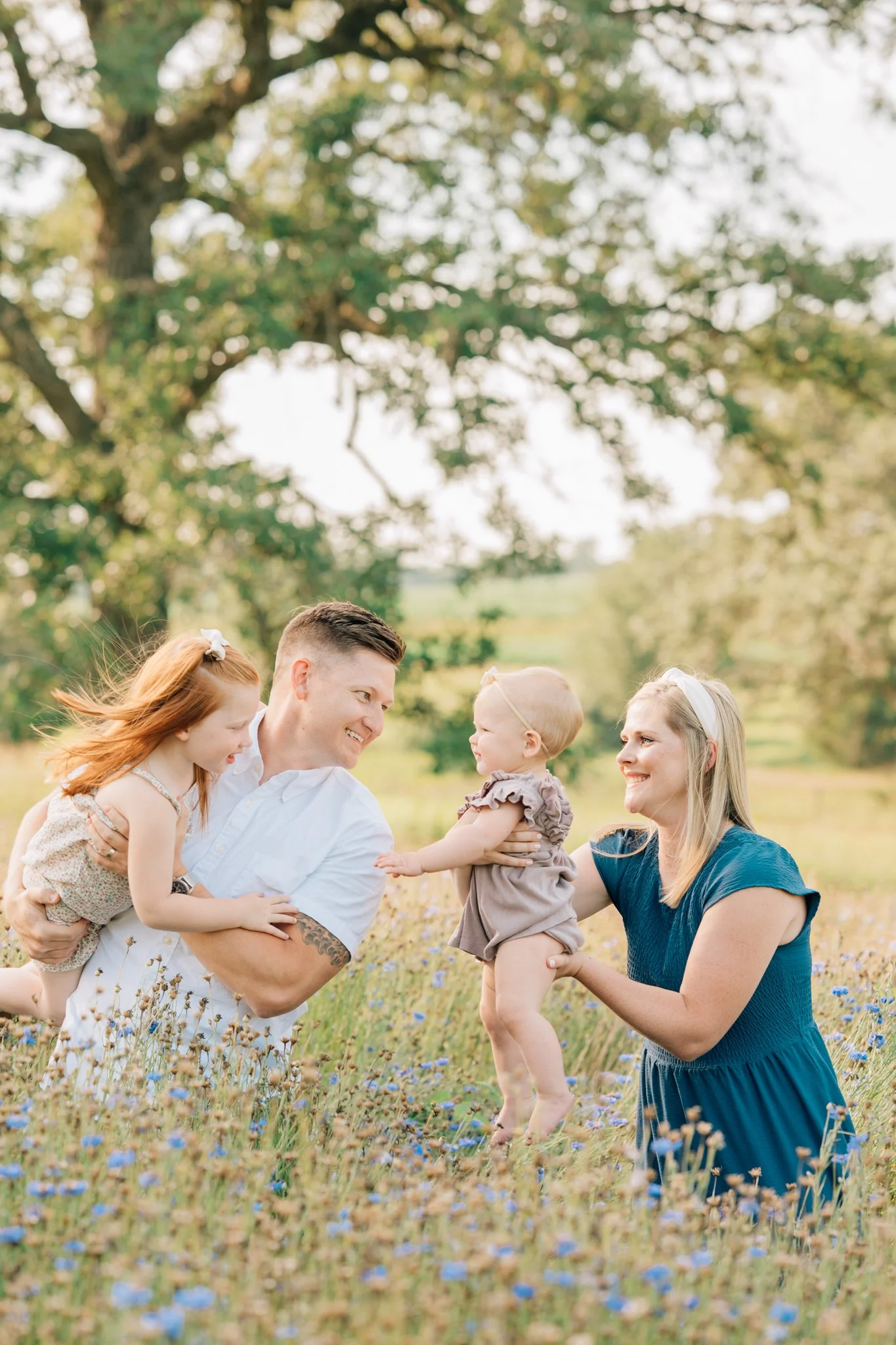 parents swinging children in wildflowers during family photo session.