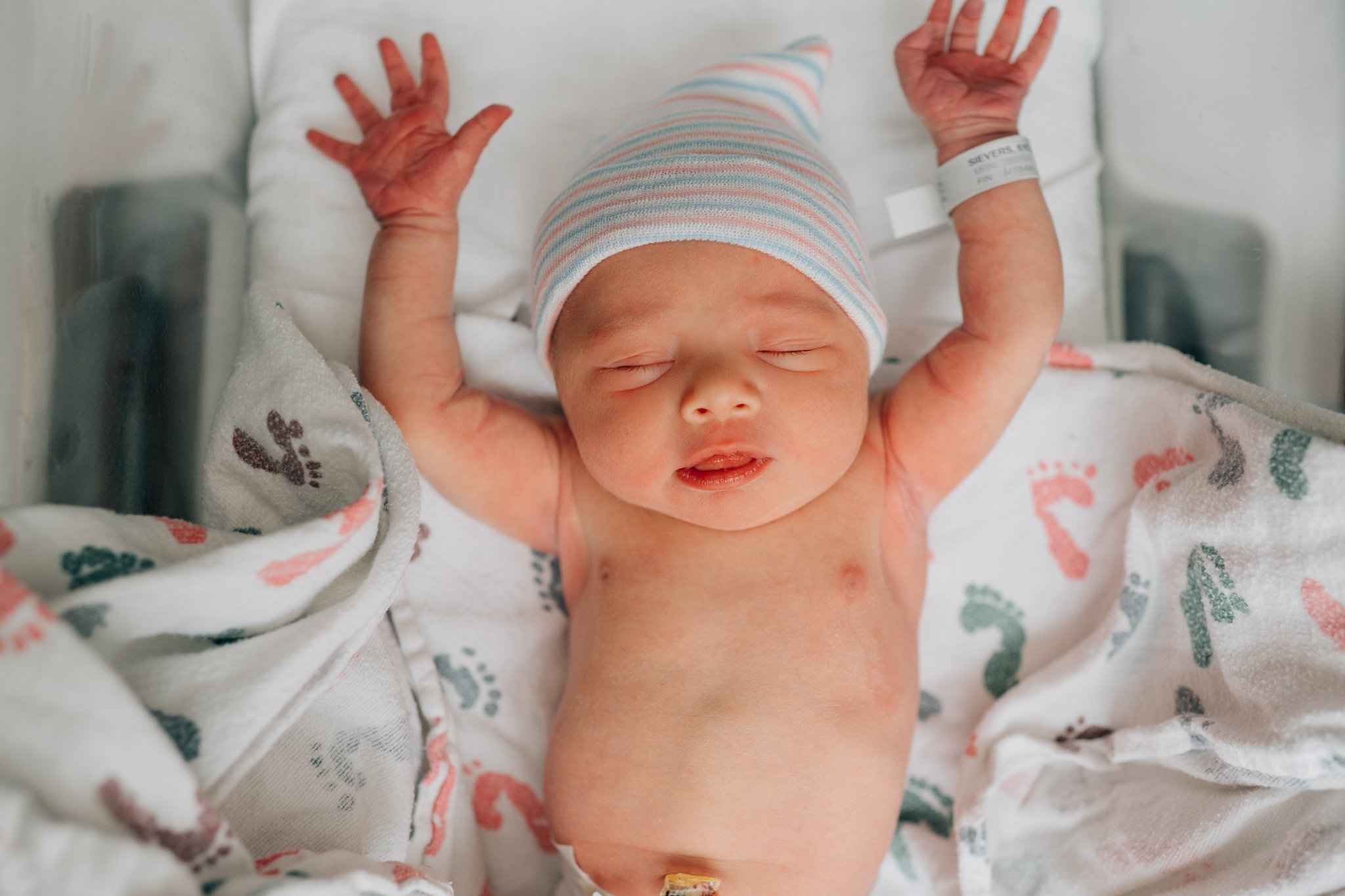 baby girl stretches in her bassinet during fresh 48 session in Iowa.