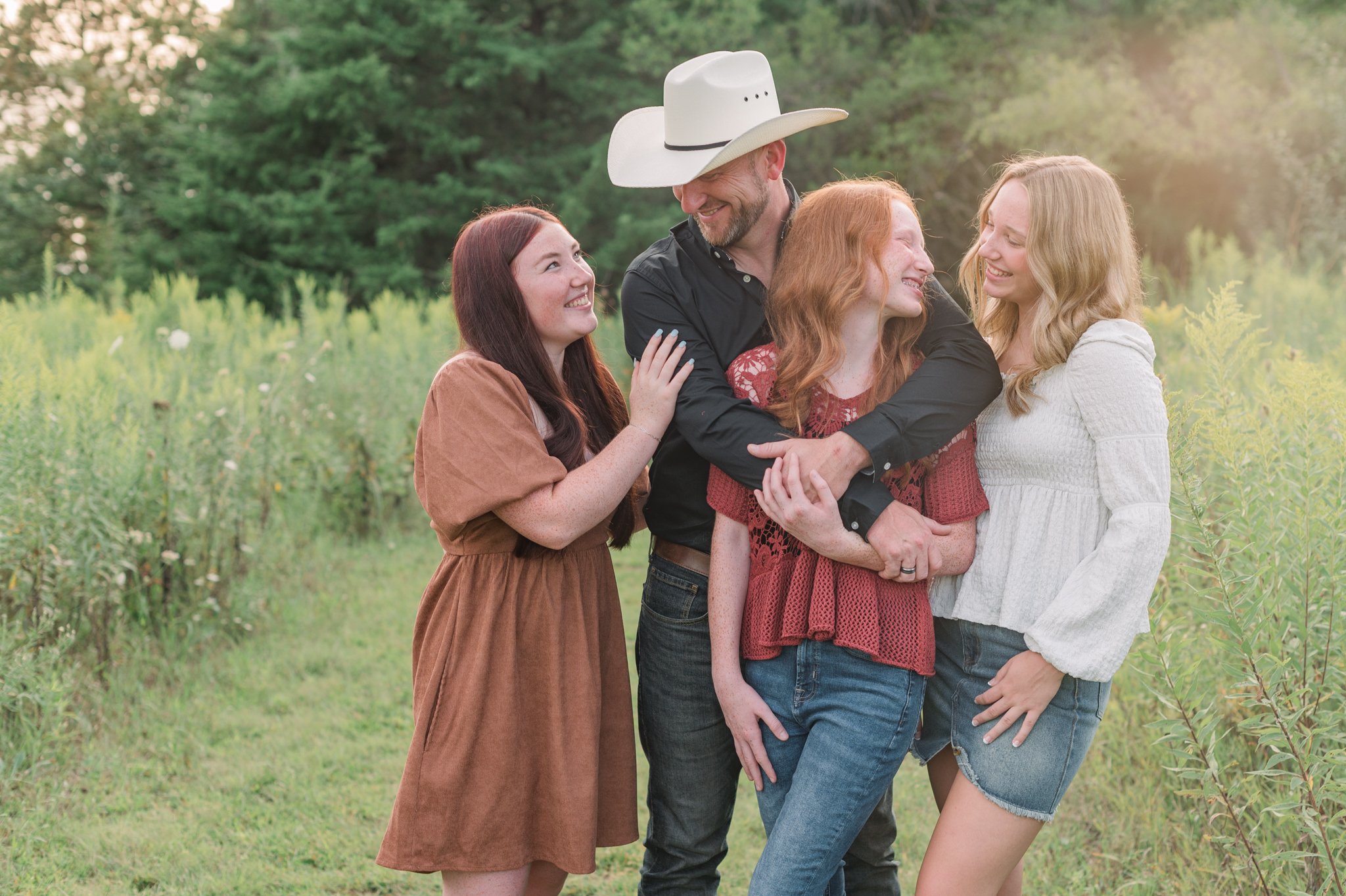 Dad and his girls laughing during family photos at sunset.