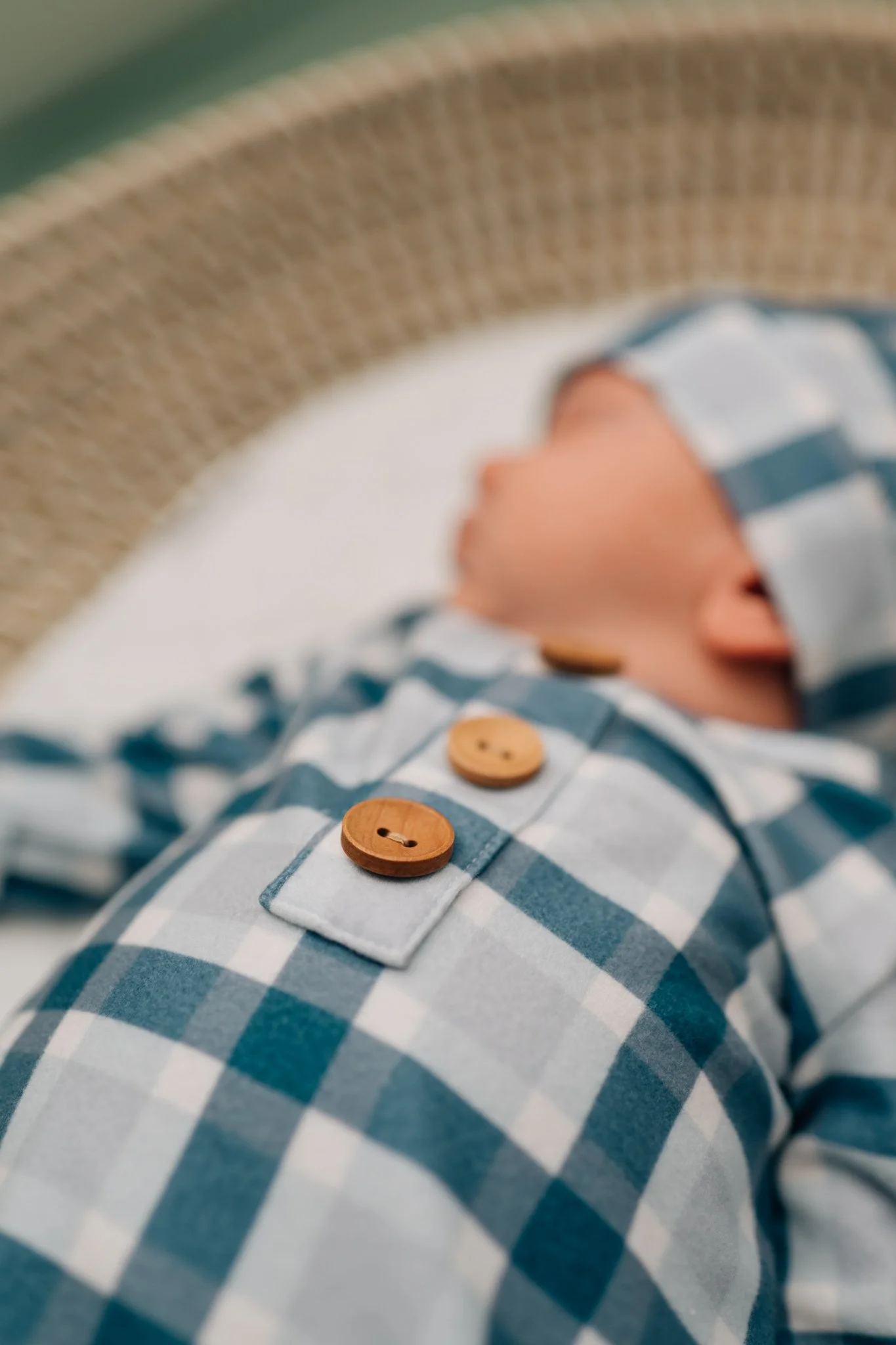 Detail of button on baby onesie during in home lifestyle newborn session in Iowa.