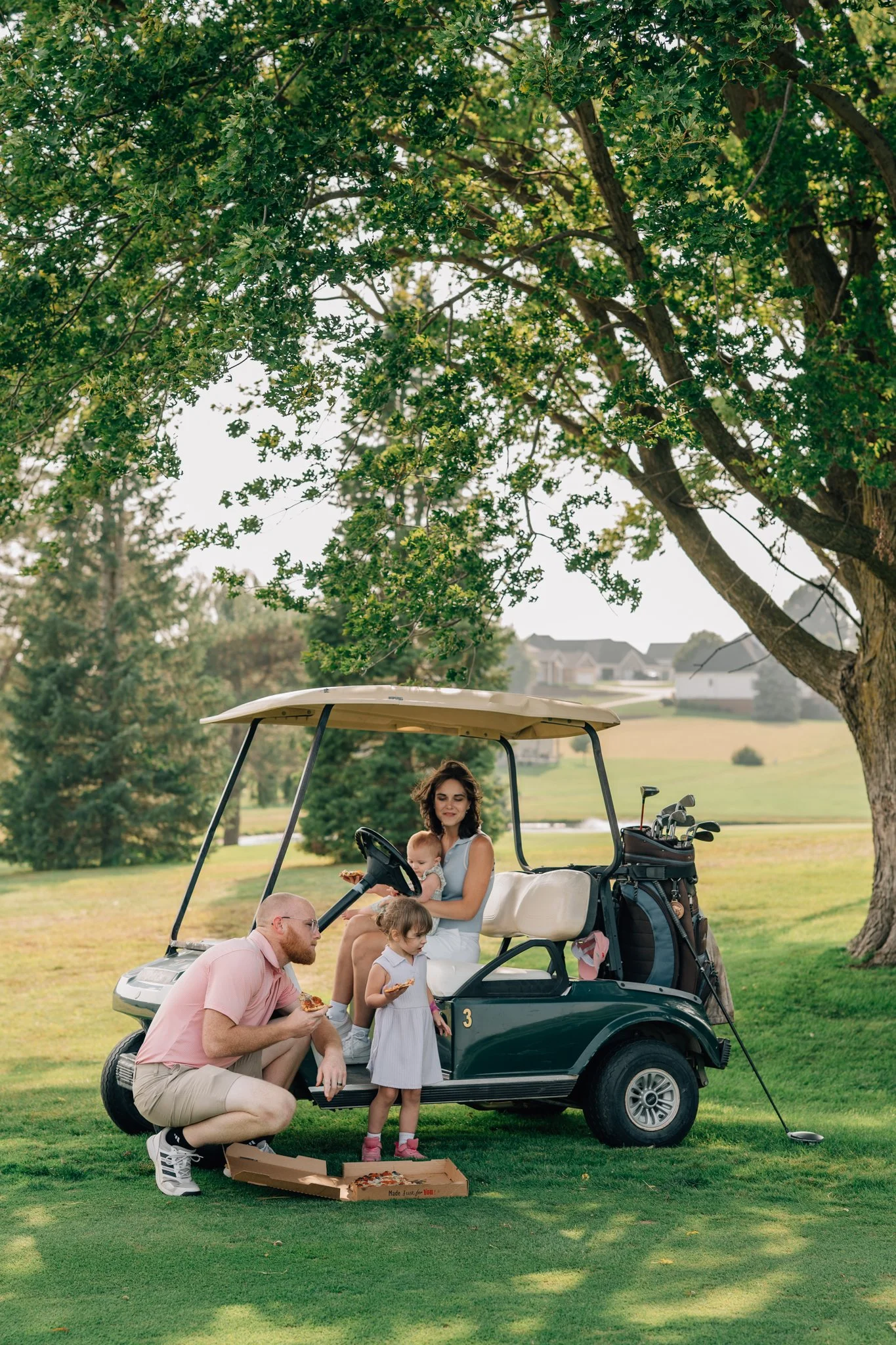 Family enjoys a night on the golf course eating pizza during their family photography session. 