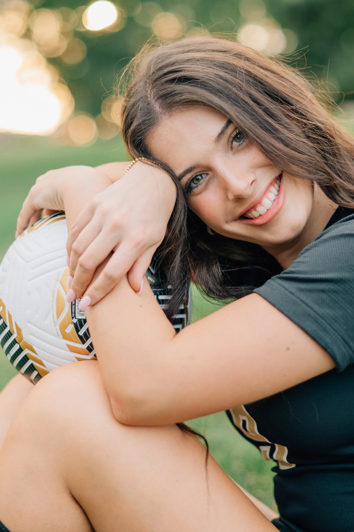 Senior photo for a young girl posed with soccer ball.