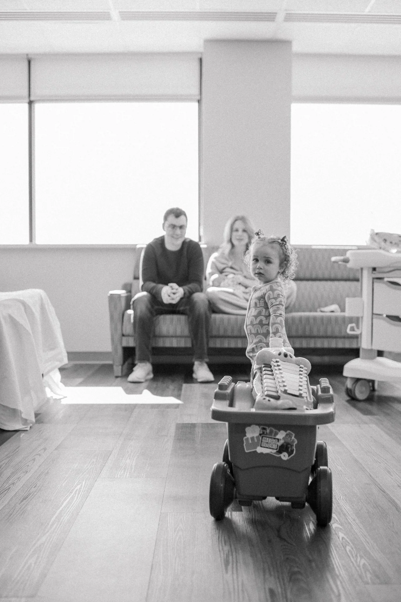 Big sister pulls wagon of toys into hospital room during fresh 48 session at Myrtue.