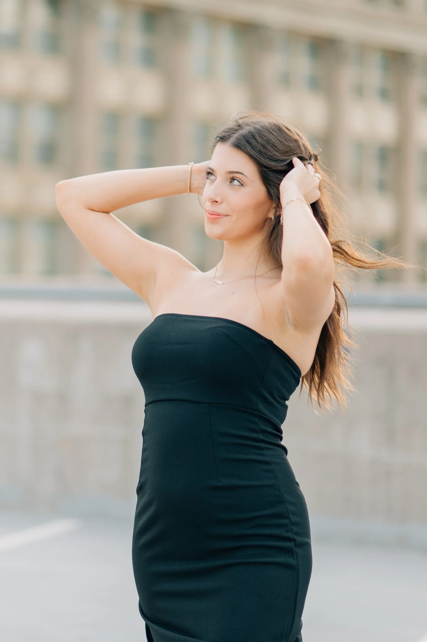 Girl on rooftop playing with her hair, posing for senior pictures in Omaha.