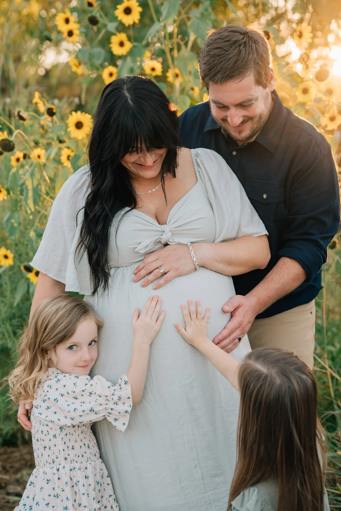 Family cuddles up to mom as they wait for newborn brother during maternity photos.