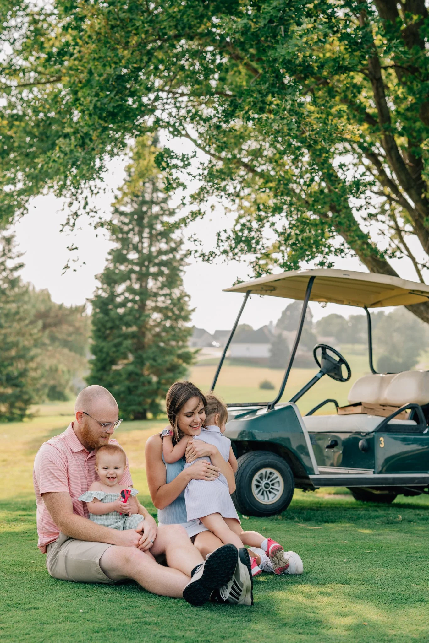 Family cuddles and laughs on golf course during summer family photography session in Iowa.