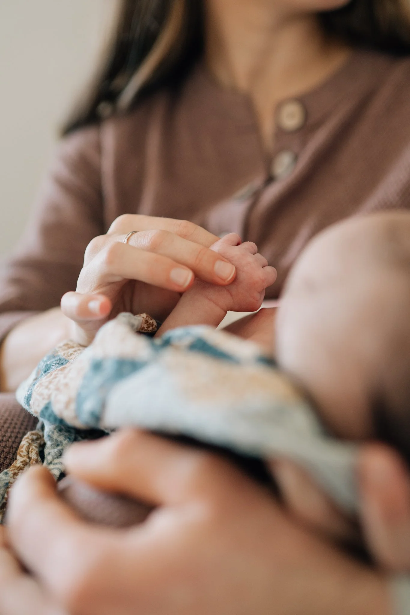 Detail photo of mom holding her newborn's hand during lifestyle newborn shoot. 