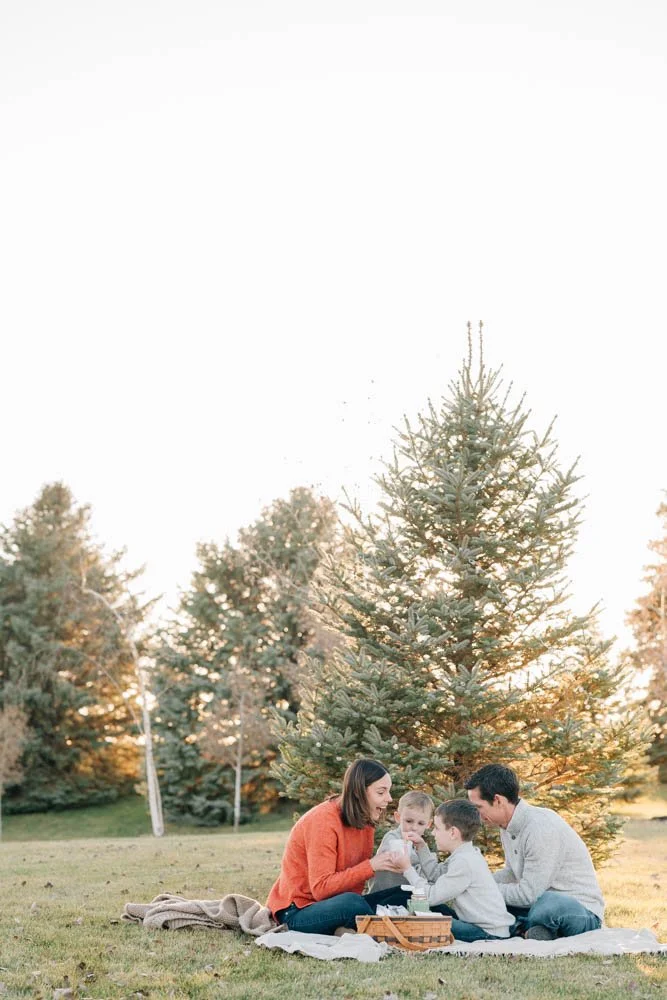 Family cuddles together on picnic blanket while drinking hot chocolate during family photos. 