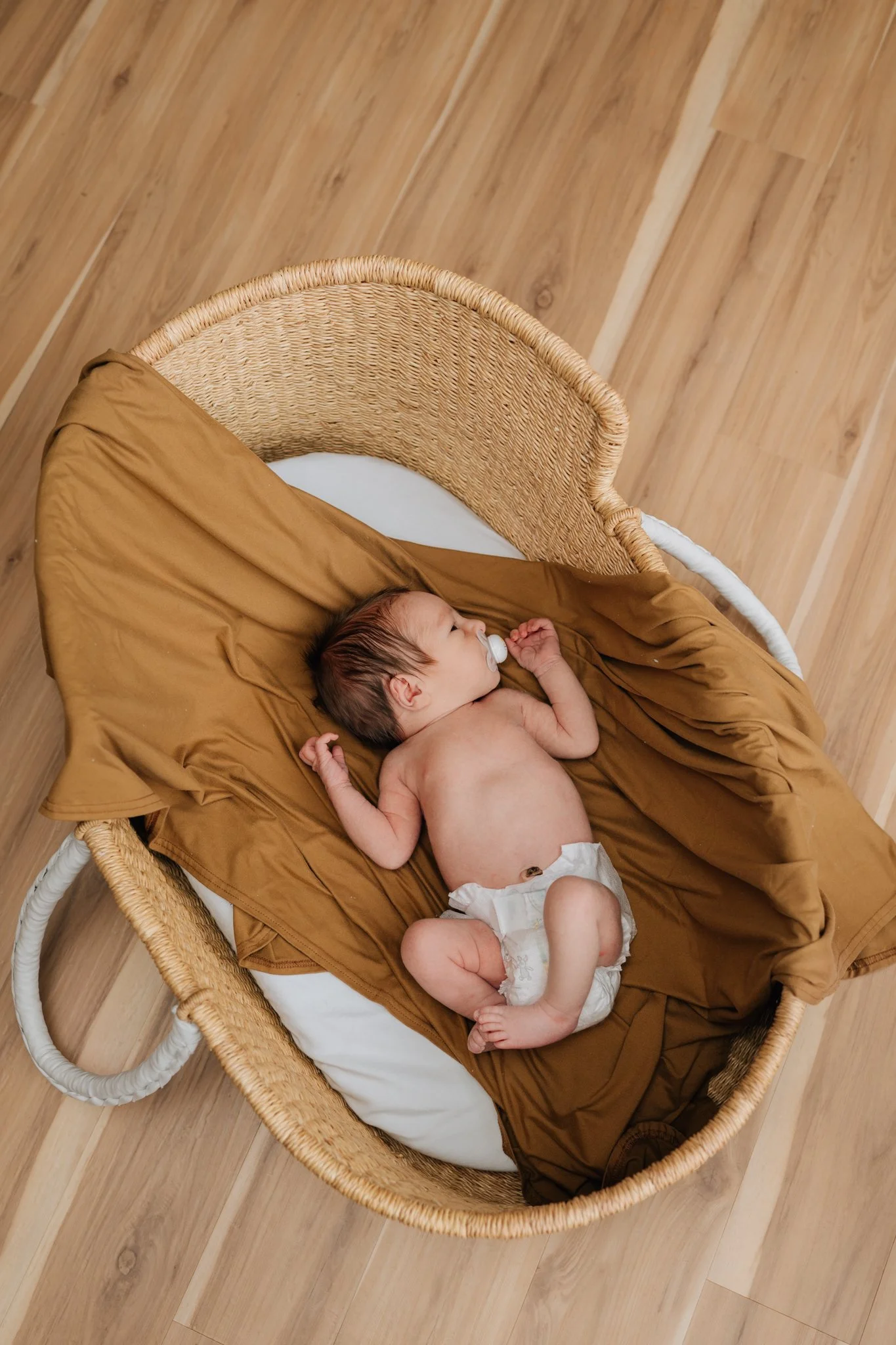 Baby boy lays in his Moses basket for newborn lifestyle shoot in his home.