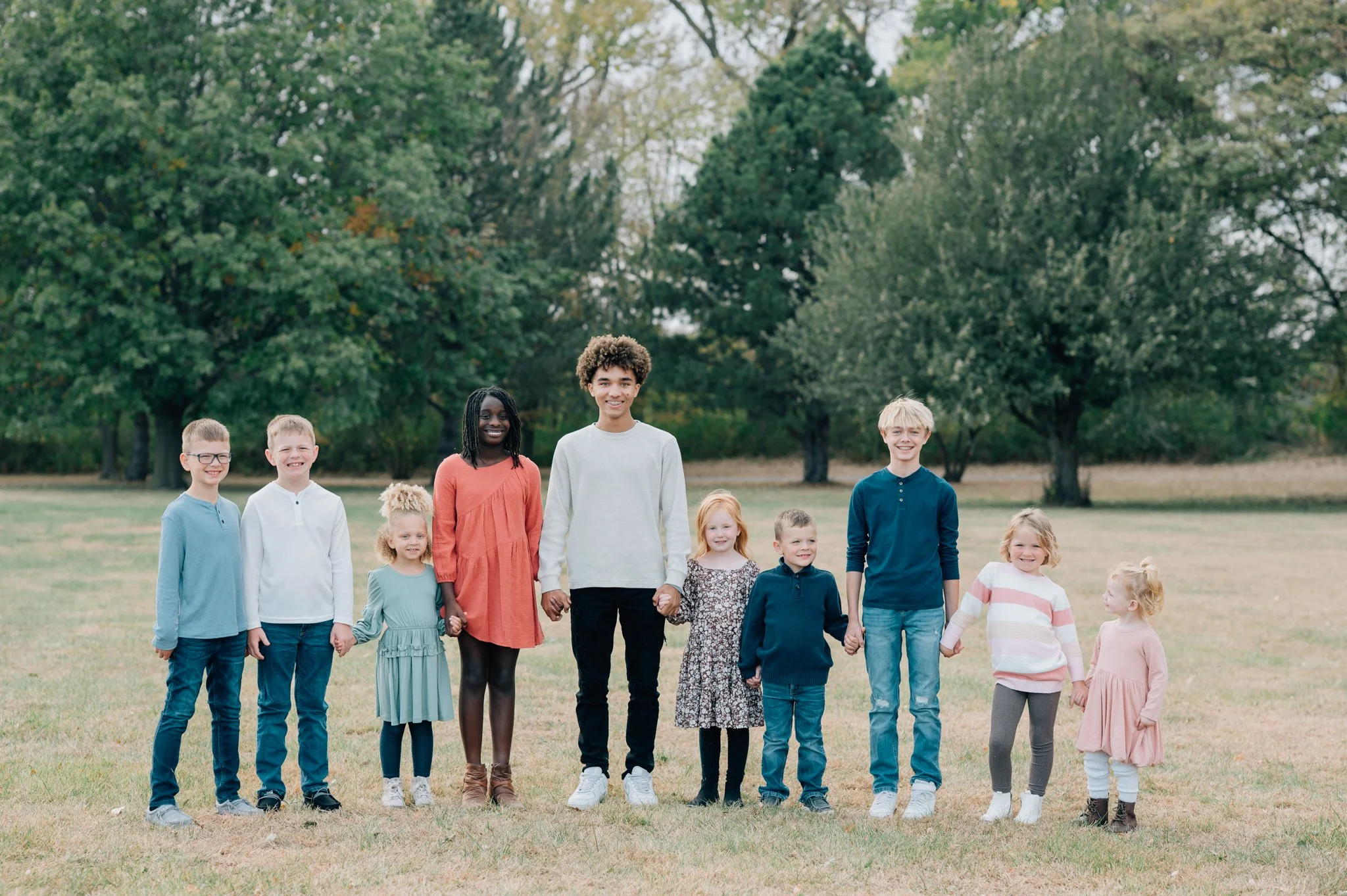 Cousins line up for photo but the youngest of the bunch smiles up to her big cousins during family photography session in Iowa.
