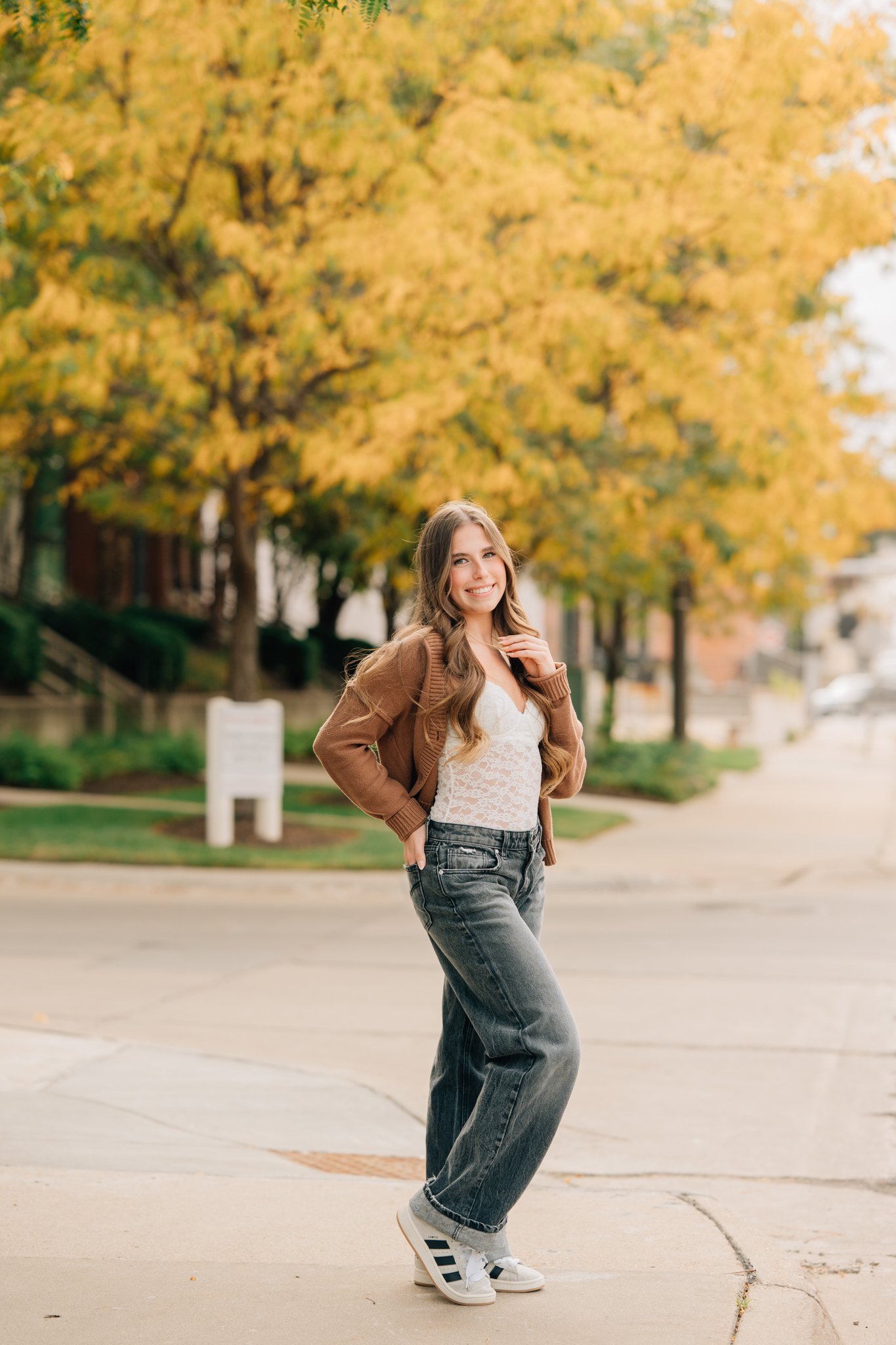 Senior girl poses in front of fall leaves during senior pictures. 
