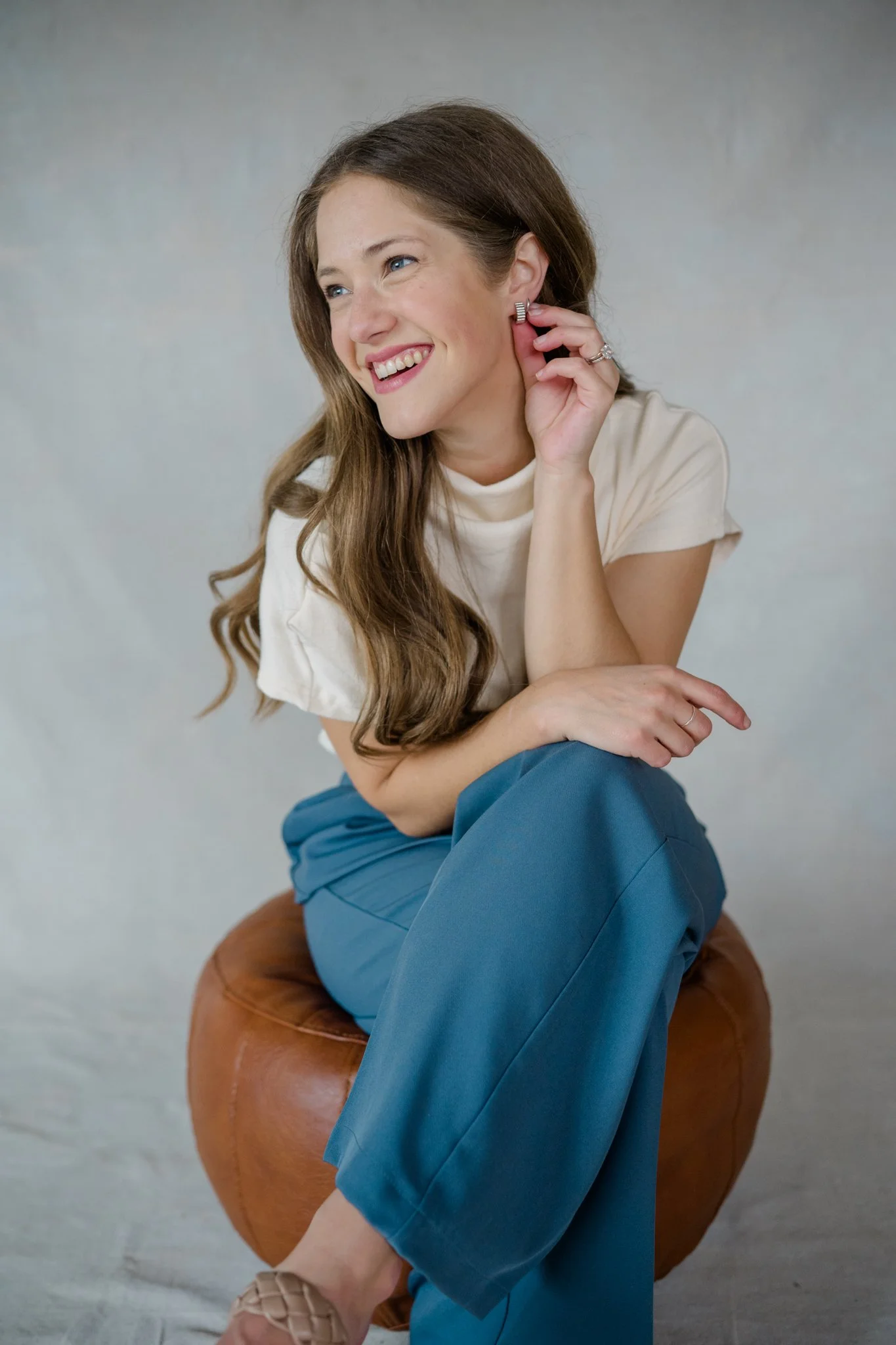 Professional headshot of woman sitting on stool, laughing for her branding photography photos.