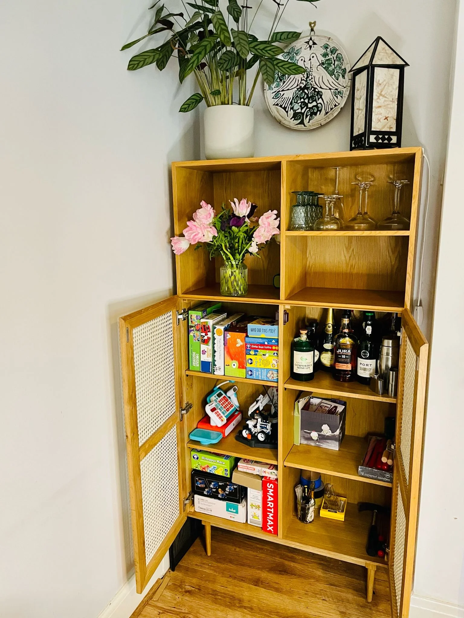professional decluttering and organising York - an organised wooden cabinet displaying arranged games, bottles, glasses, and flowers