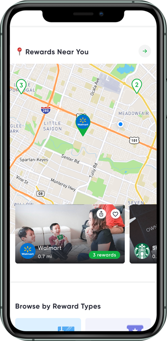 Smartphone screen displaying a map with nearby rewards and store locations, including Walmart. A banner shows a family with text offering 3 rewards at Walmart, 0.7 miles away.