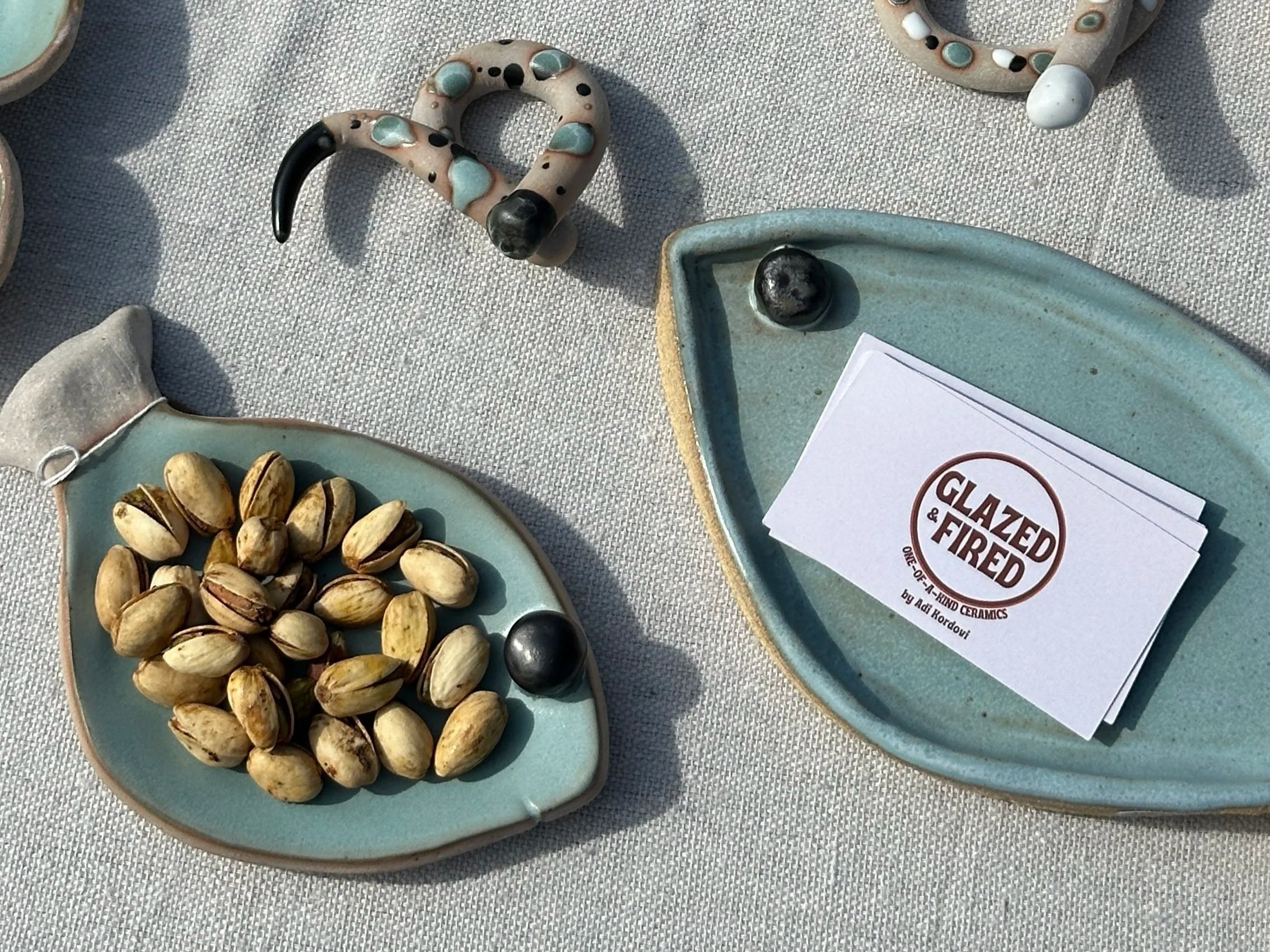 Fish plates on a table, one of them holding pistachios and the other holding business cards.