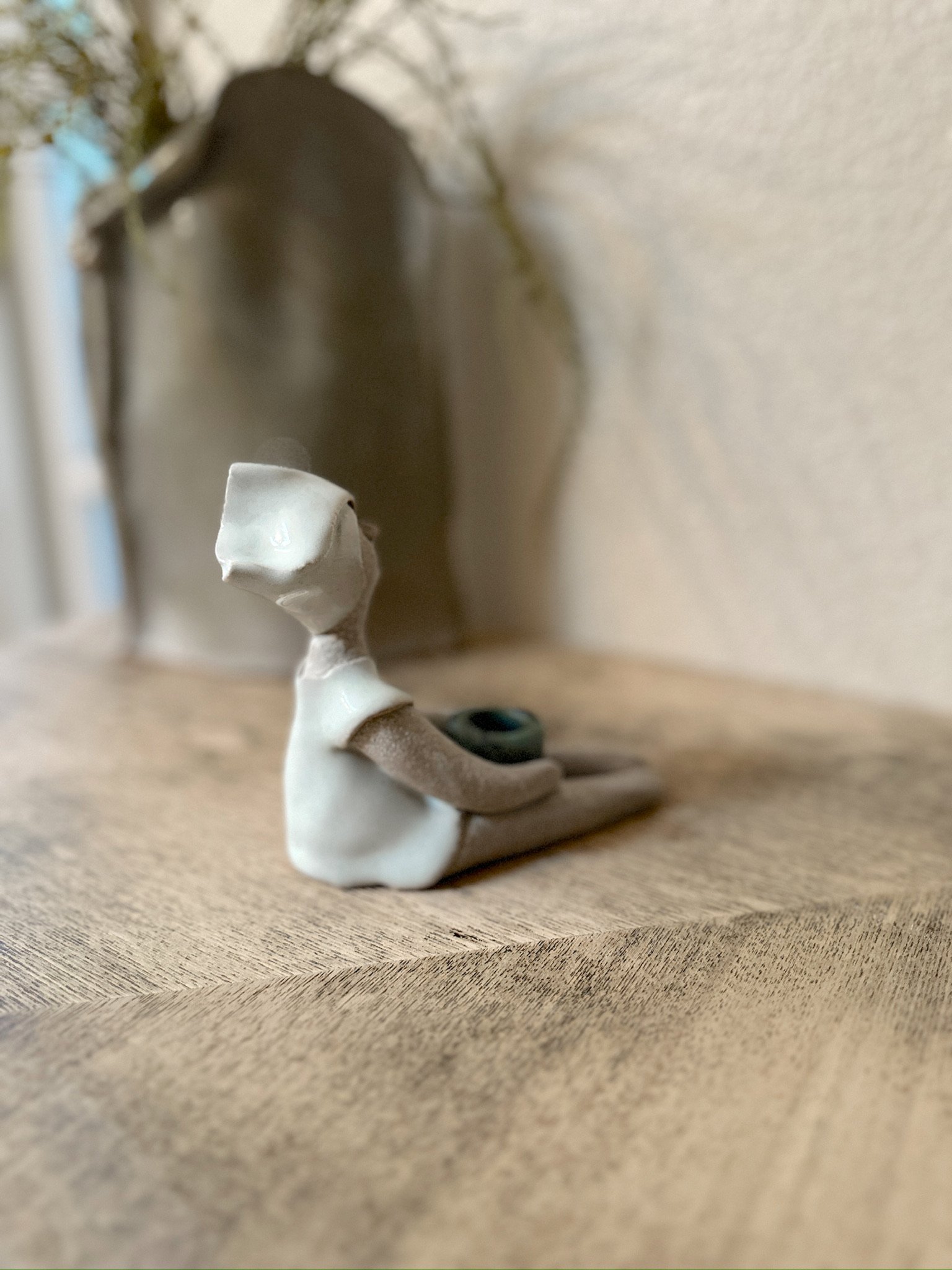 Glazed and Fired ceramic handmade sculpture of a lady holding a small blue bowl and sitting on a table. Image from the right.