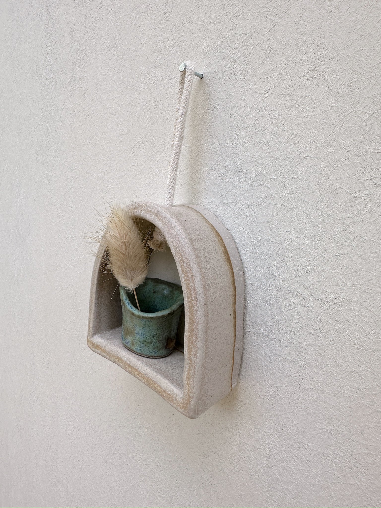 Glazed and Fired ceramic handmade rounded frame with a flat bottom with a small turquoise vase. Image from the right.