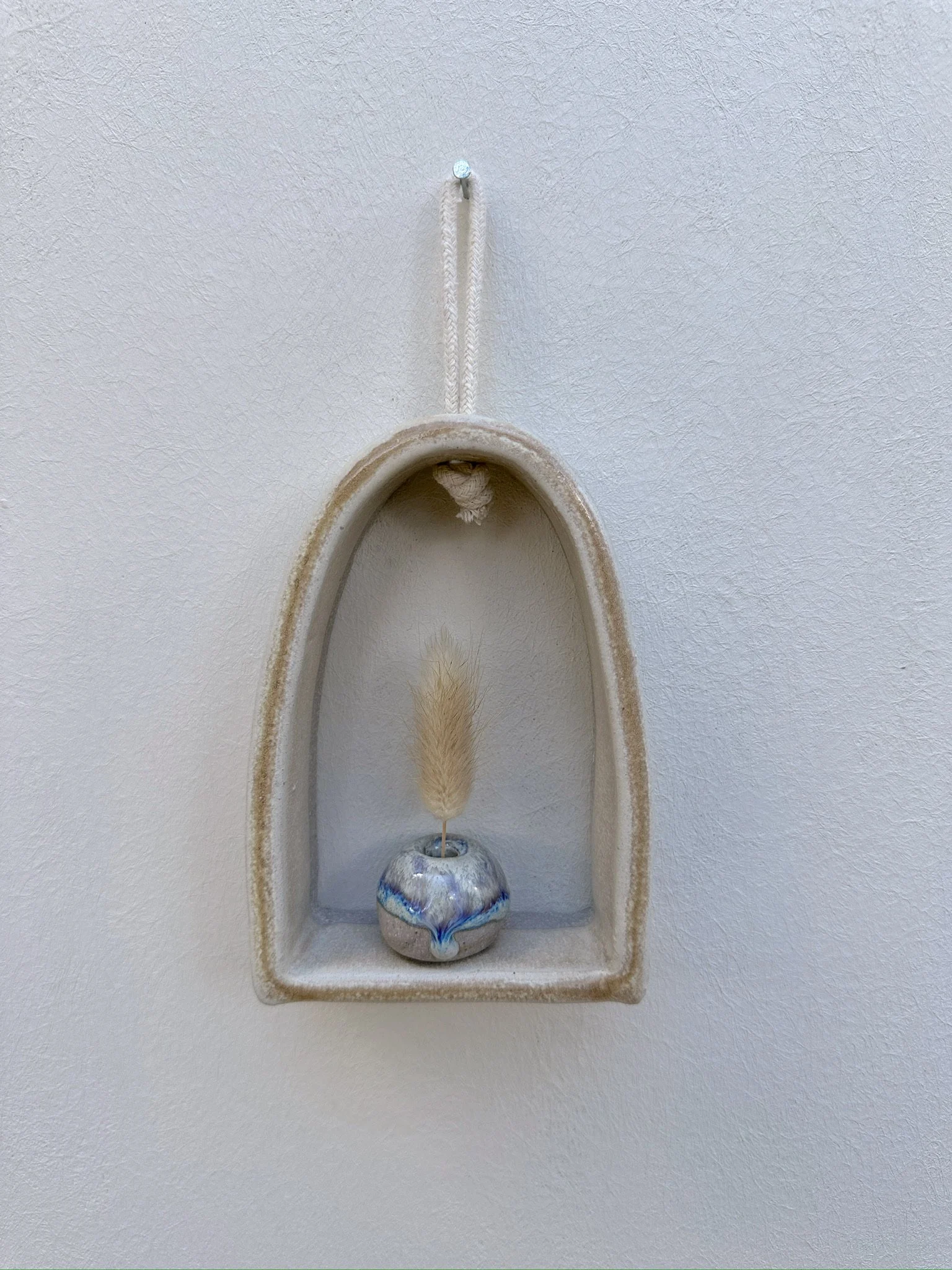 Glazed and Fired ceramic handmade rounded frame with a flat bottom with a light blue vase. Image from the front