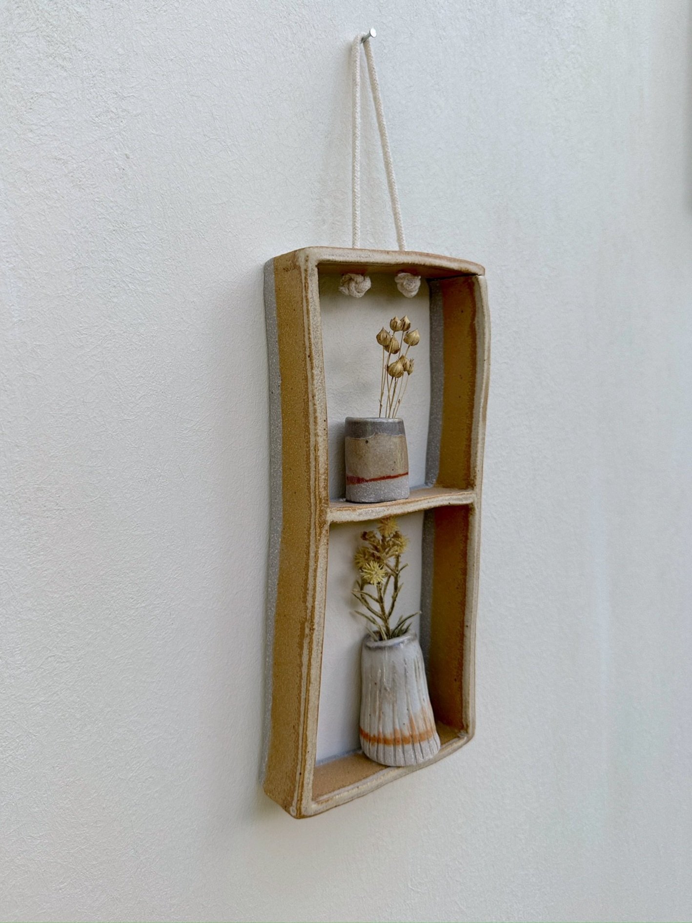 Glazed and Fired ceramic handmade two-tiered frame with two small grey/rust vases. Image from the left.