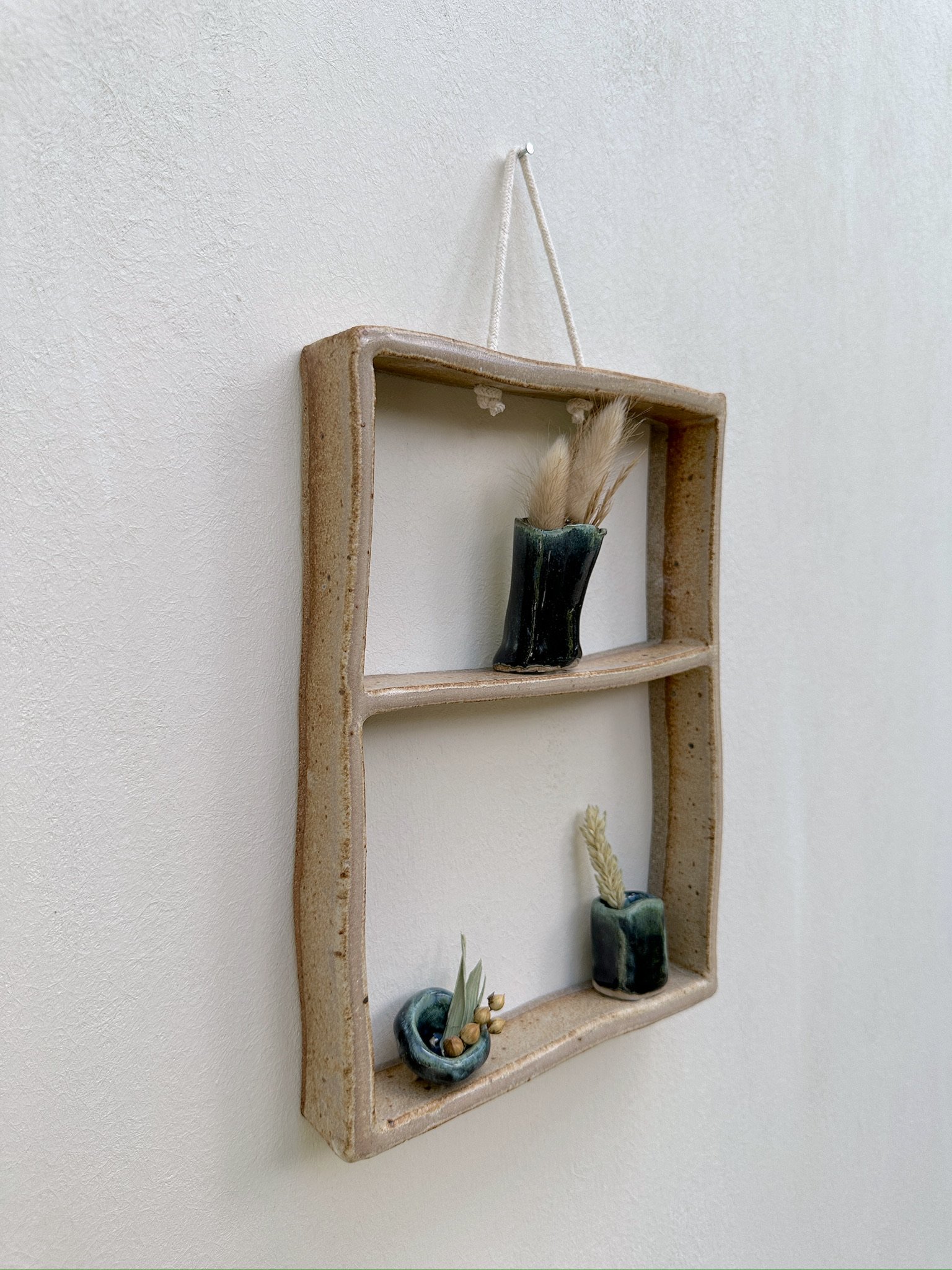 Glazed and Fired ceramic handmade two-tiered frame with three dark blue vases. Image from the left.