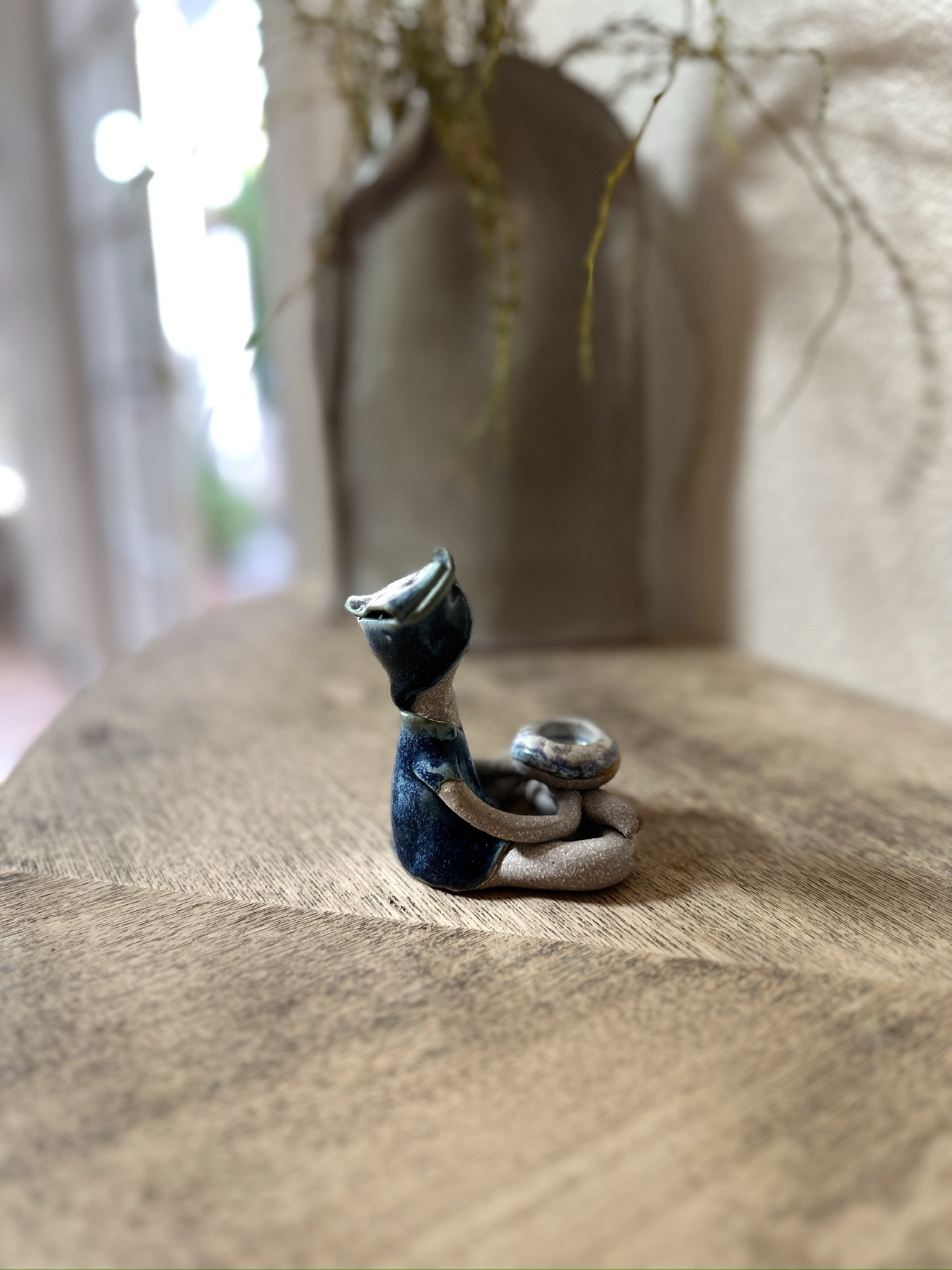 Glazed and Fired ceramic handmade sculpture of a lady with an incense holder and sitting cross-legged on a table. Image from the right.
