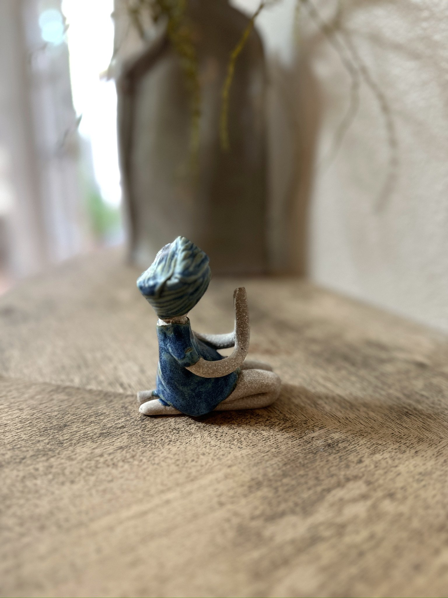 Glazed and Fired ceramic handmade sculpture of a lady with her hands in a prayer position and sitting on her knees on a table. Image from the right.