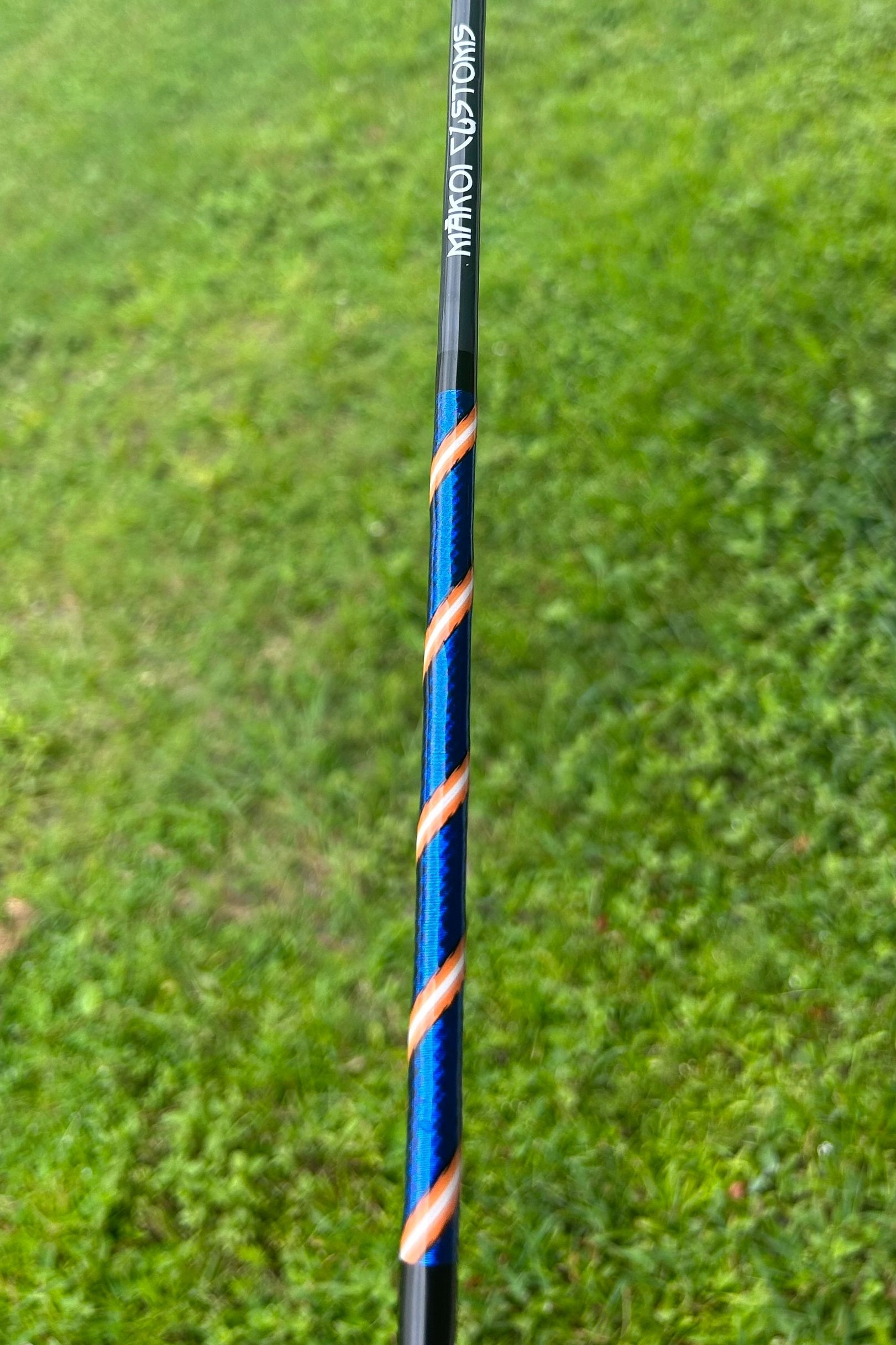Fishing rod with blue and orange spiral design on grass background.