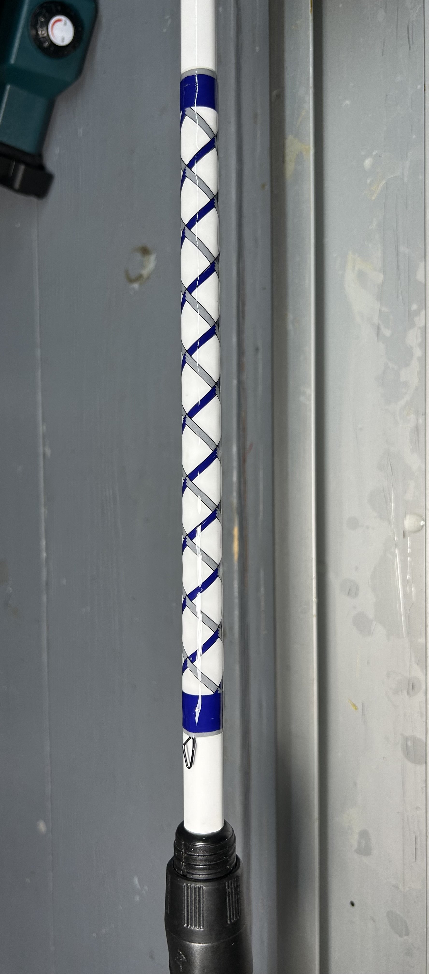 Close-up of a fishing rod with blue and white decorative wrap on the handle.