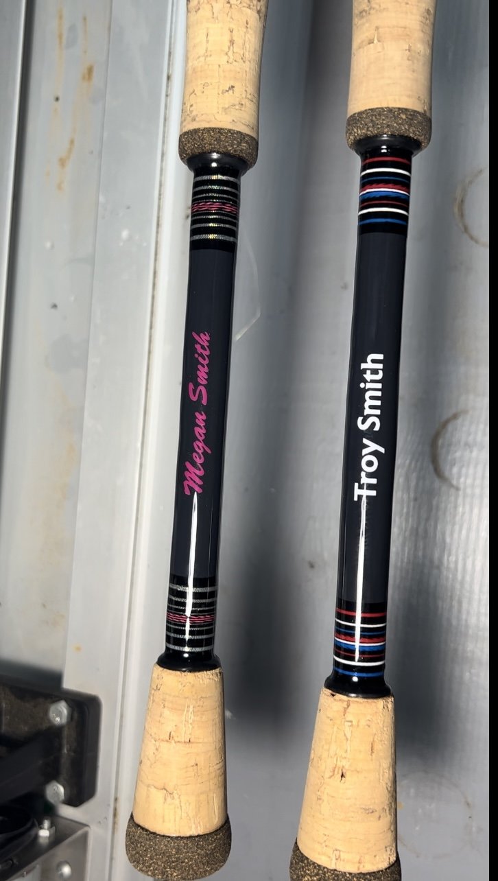 Custom fishing rods with cork handles and personalized names "Megan Smith" and "Troy Smith" on the shafts.