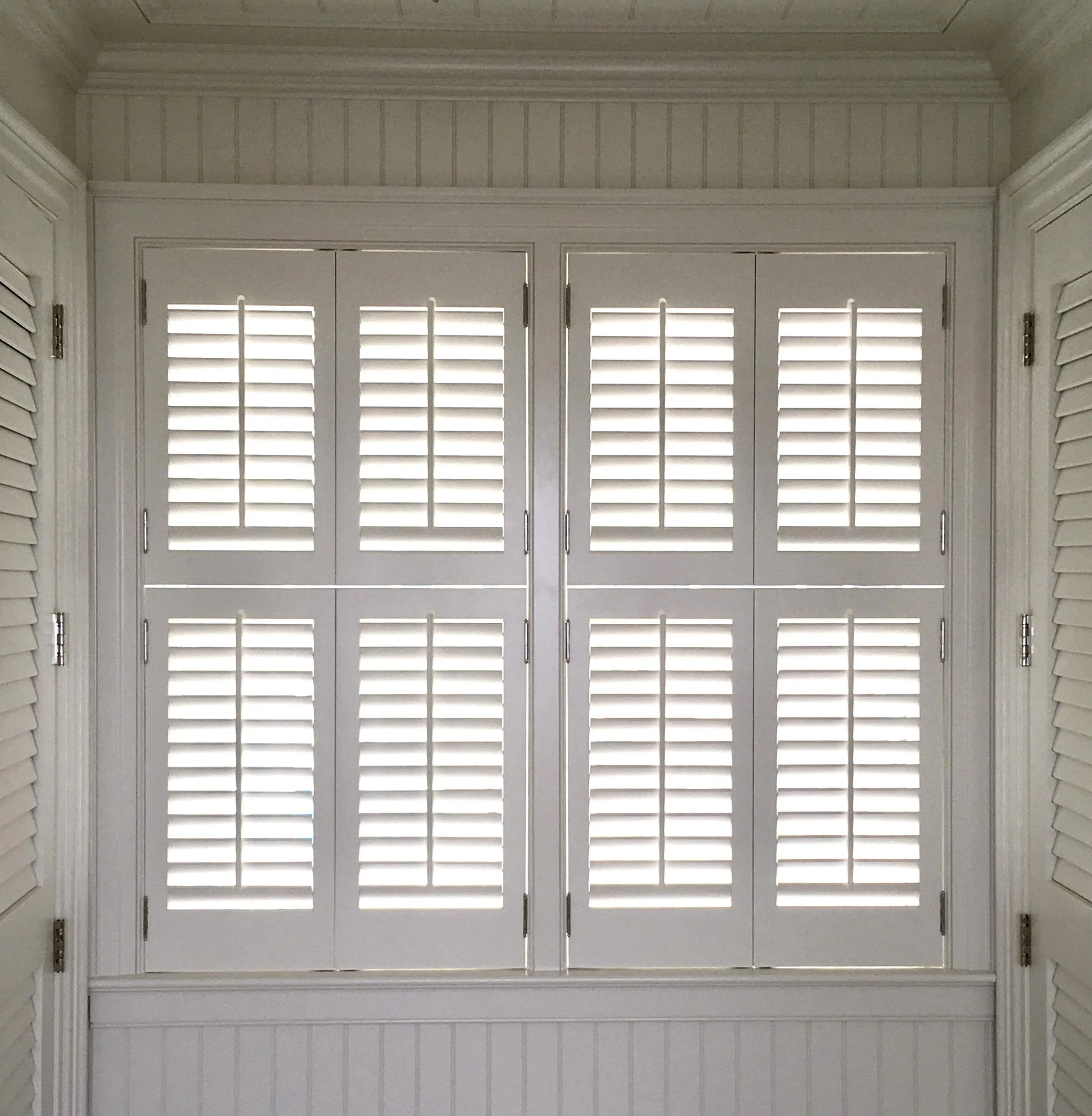 White interior window shutters with horizontal slats in a closed position.