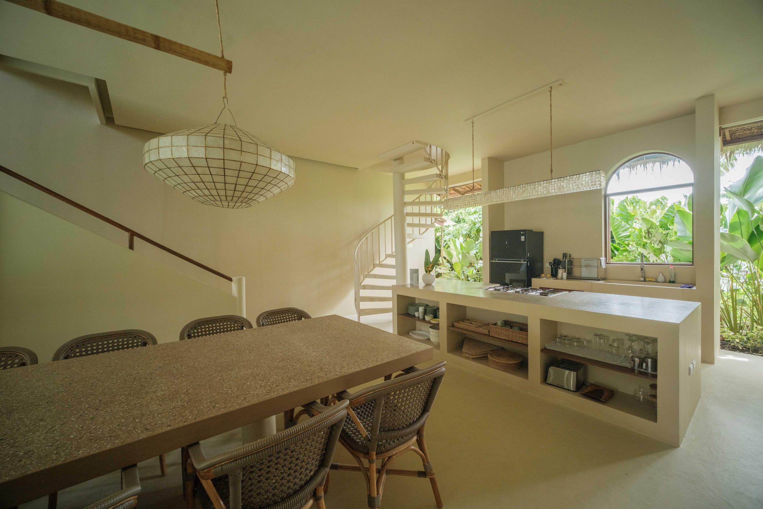 Shared dining and kitchen space at schönhouse Villa Siargao with long dining table, natural light and tropical garden views in General Luna.