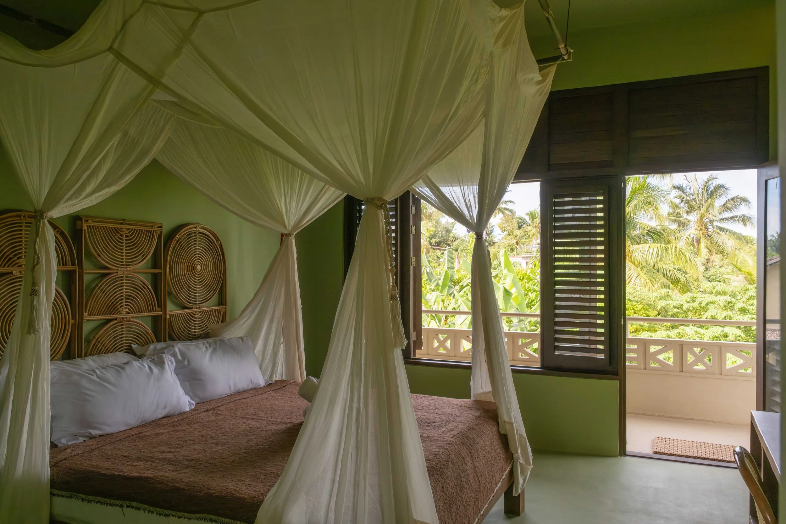 Couple Suite at schönhouse Villa Siargao with canopy bed, balcony and tropical greenery views.