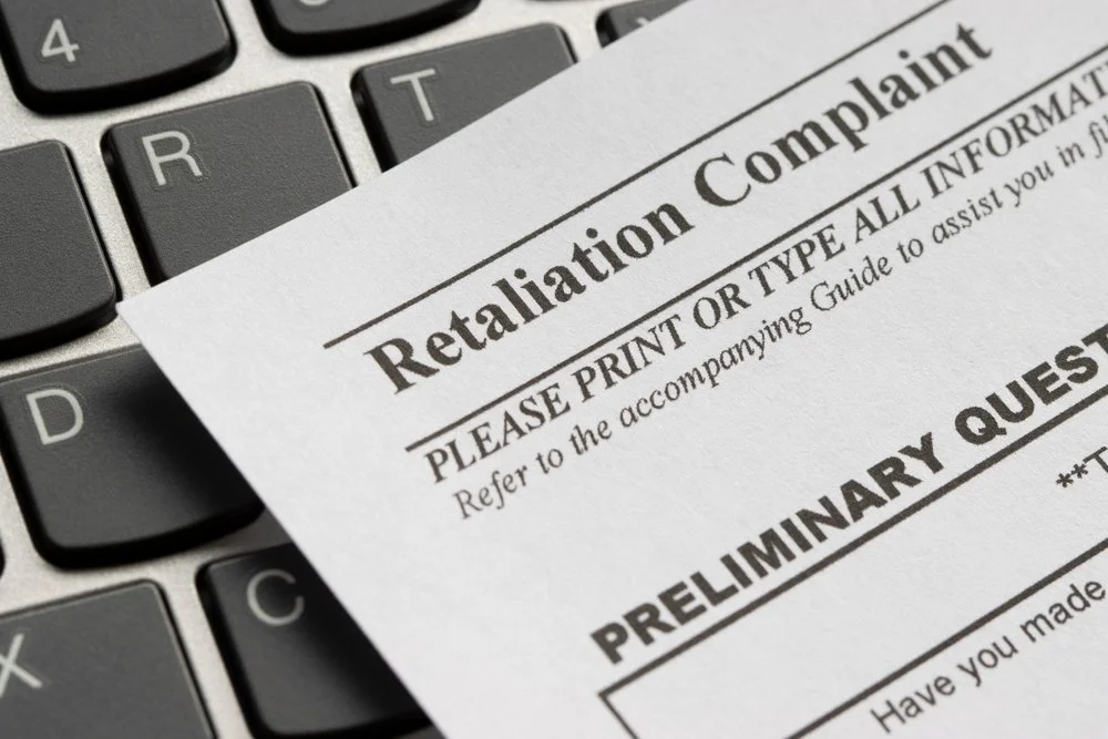 A form titled "Retaliation Complaint" rests on a laptop keyboard.