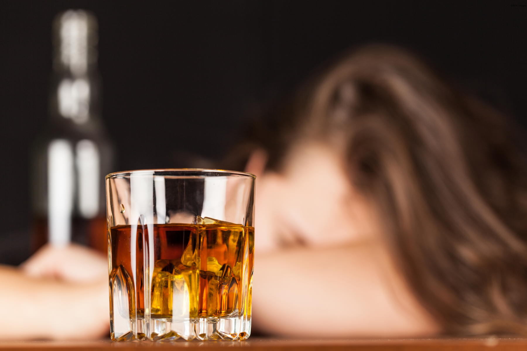 Women passed out at bar, with a glass of scotch in front of her