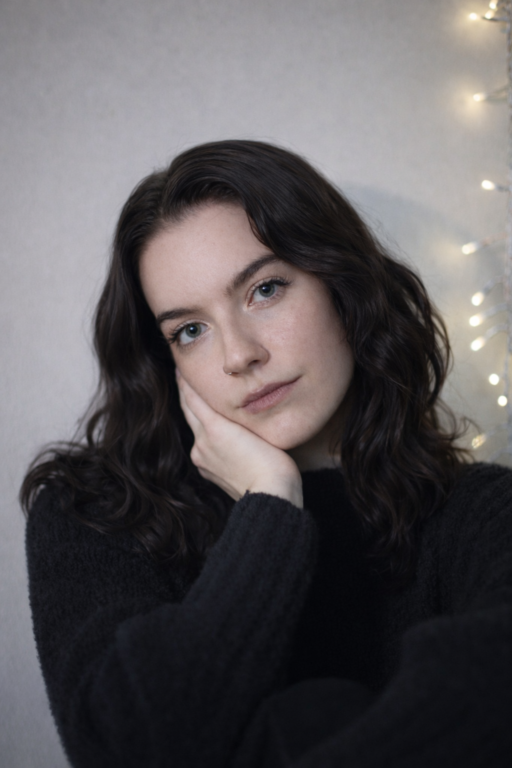 Portrait of Myself with a black sweater and fairy lights in the background.