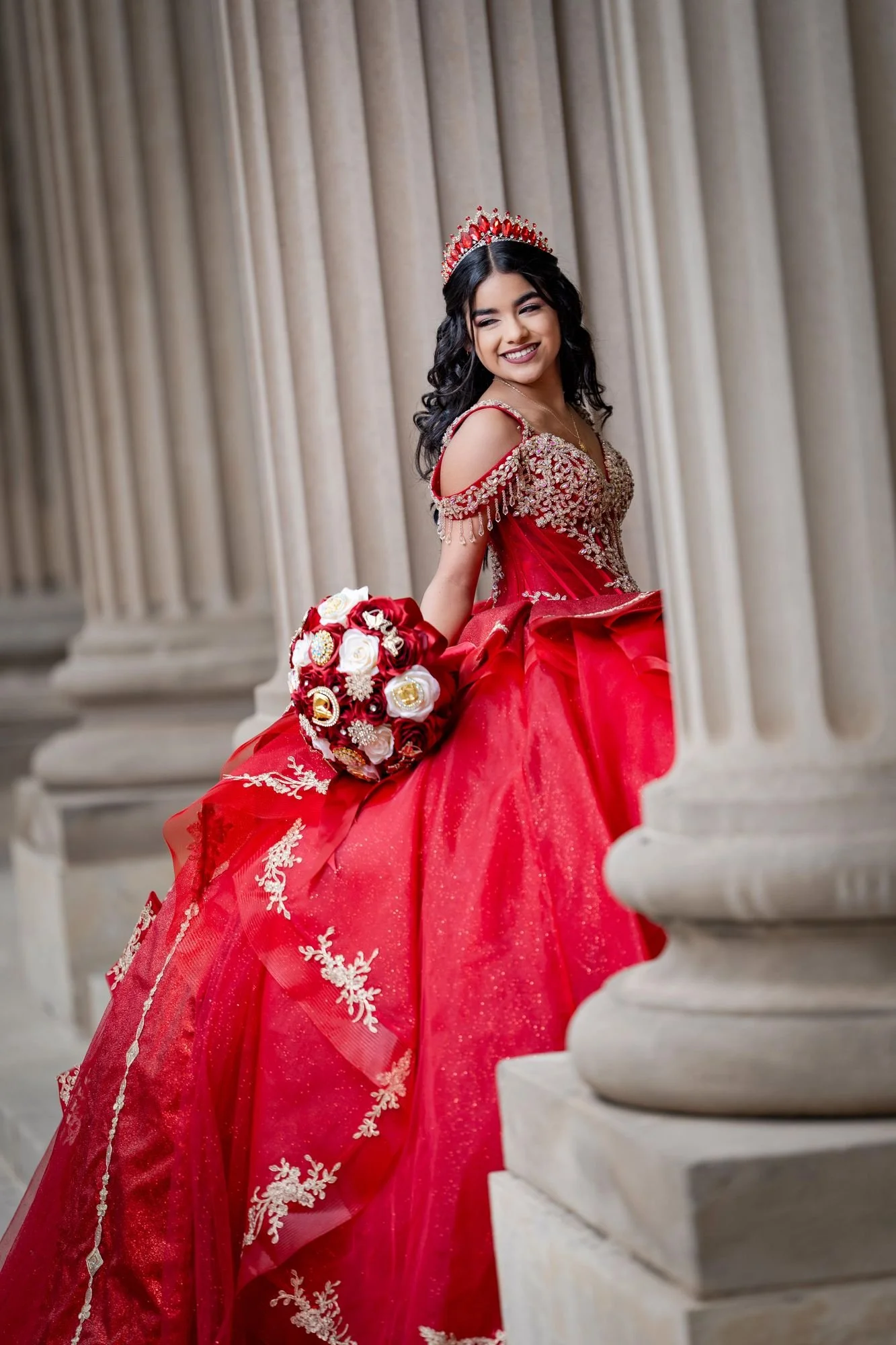 Red quinceañera ballgown portrait between the massive columns of the Scottish Rite Cathedral in Dallas, showing the bodice beadwork and structured tulle construction