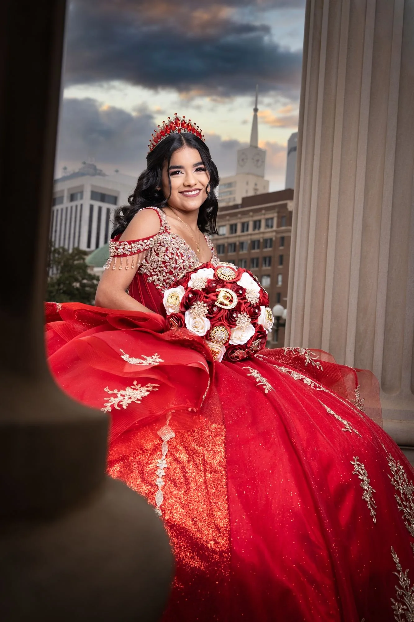 Red quinceañera ballgown from Rafaela's Gowns with gold embroidery, photographed at sunset at the Scottish Rite Cathedral in downtown Dallas