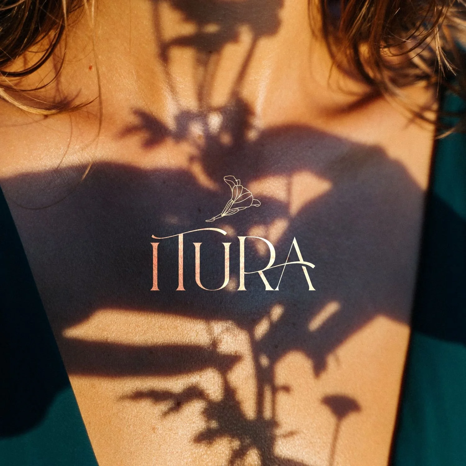 Close-up of a person's collarbone with shadow of a flower, and the text 'IÍURA' with a butterfly illustration.