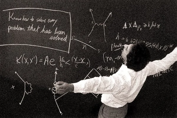 Man with his arms raised wide facing a blackboard full of diagrams and equations