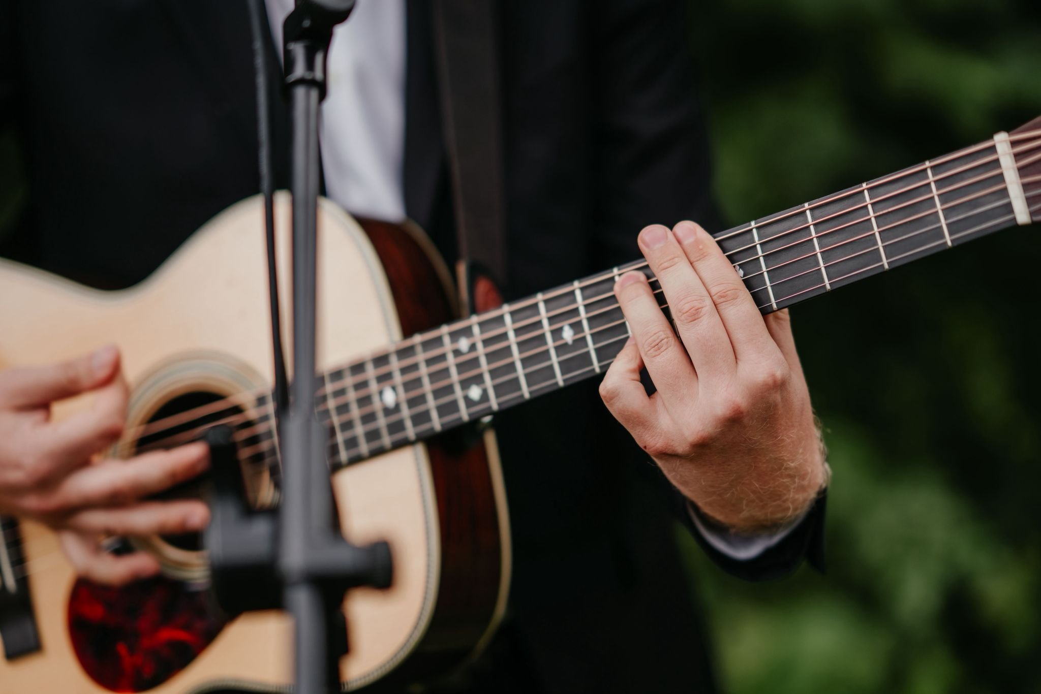 Nahaufnahme einer Person, die auf einer akustischen Gitarre spielt, mit Fokus auf die Finger auf den Saiten.