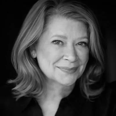Black and white portrait of a woman with shoulder-length hair, smiling softly at the camera.