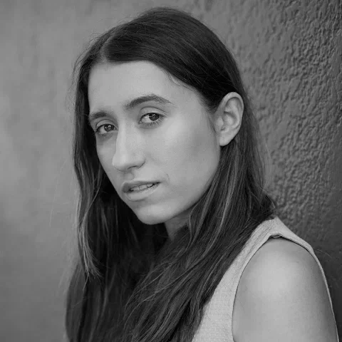 Black and white portrait of a young woman with long hair looking at the camera.