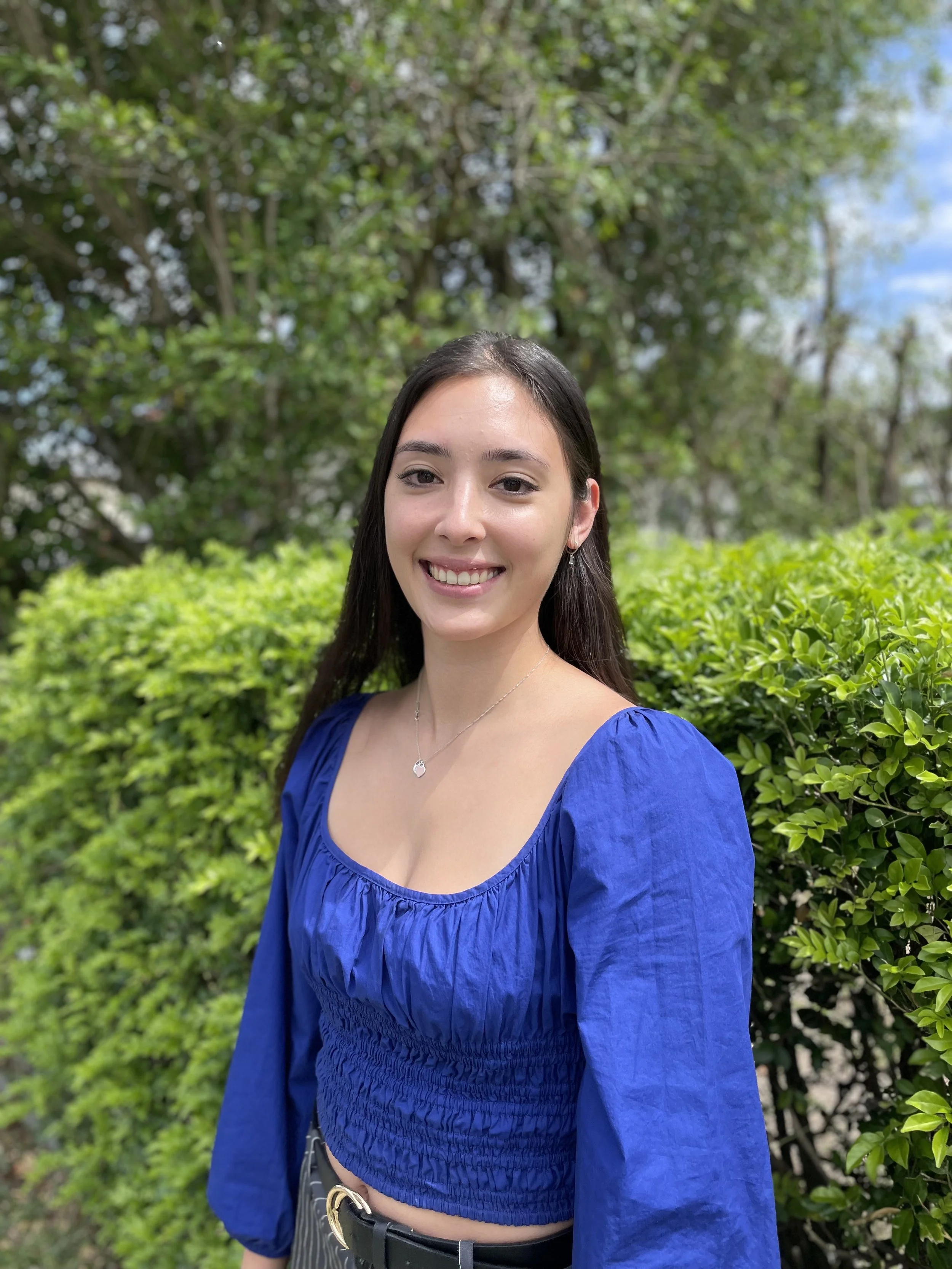 Smiling dark-haired woman wearing a bright blue blouse