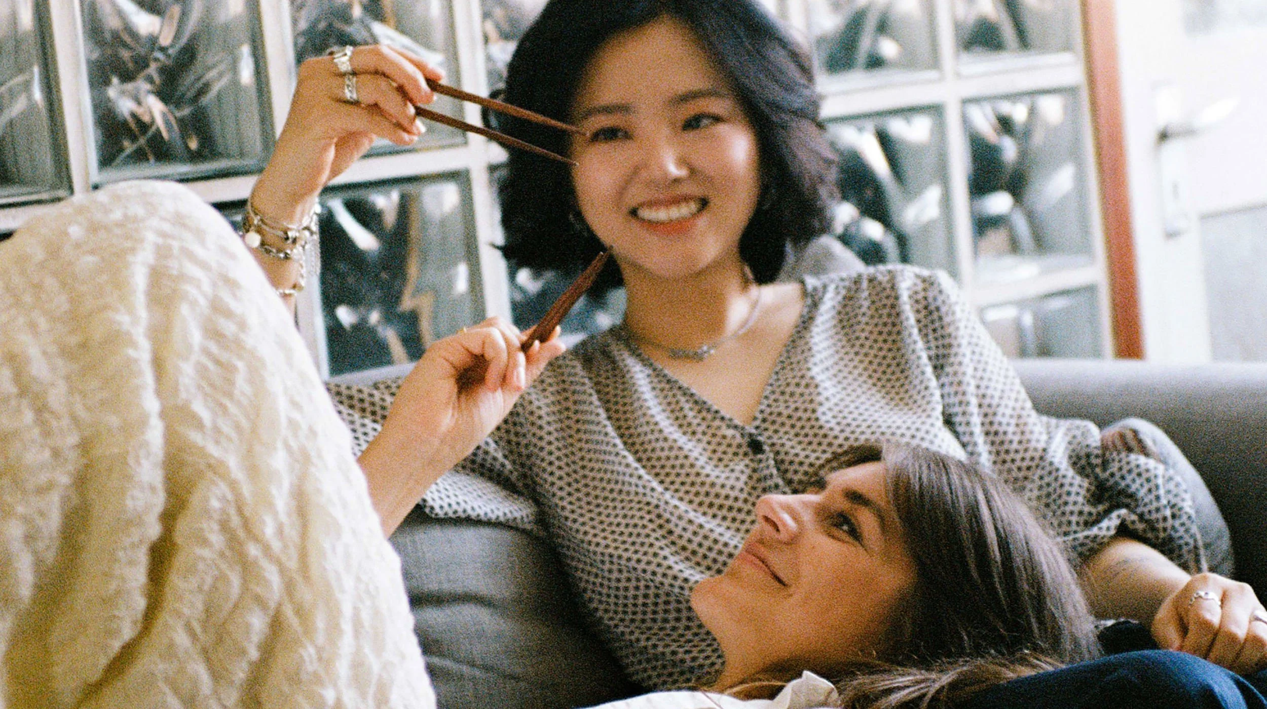 The Ferm's co-founders Rebecca Ghim & Maylin Stanic on a sofa eating with chopsticks